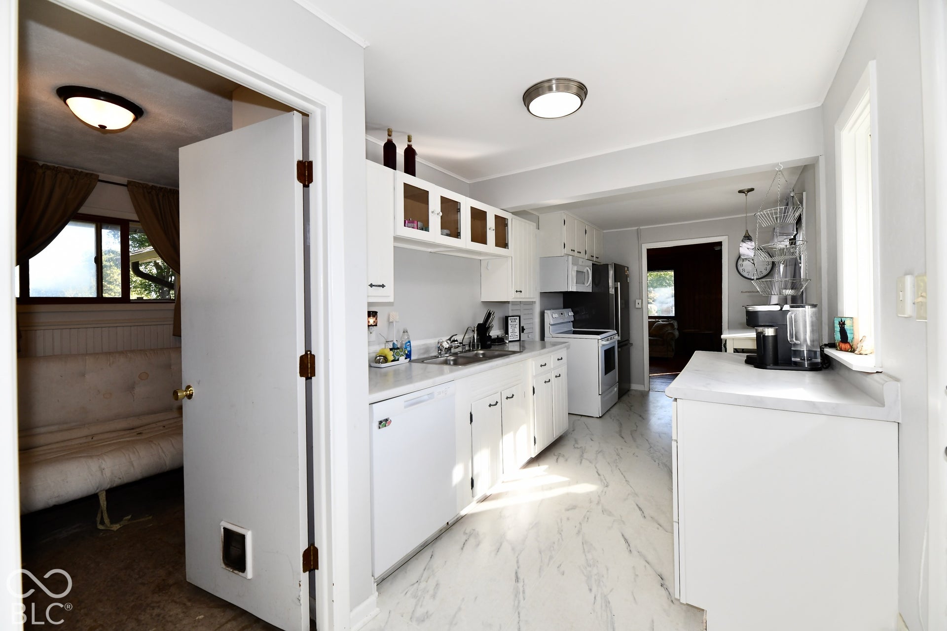 Kitchen featuring white cabinetry, white countertops, stainless steel refrigerator, white electric range