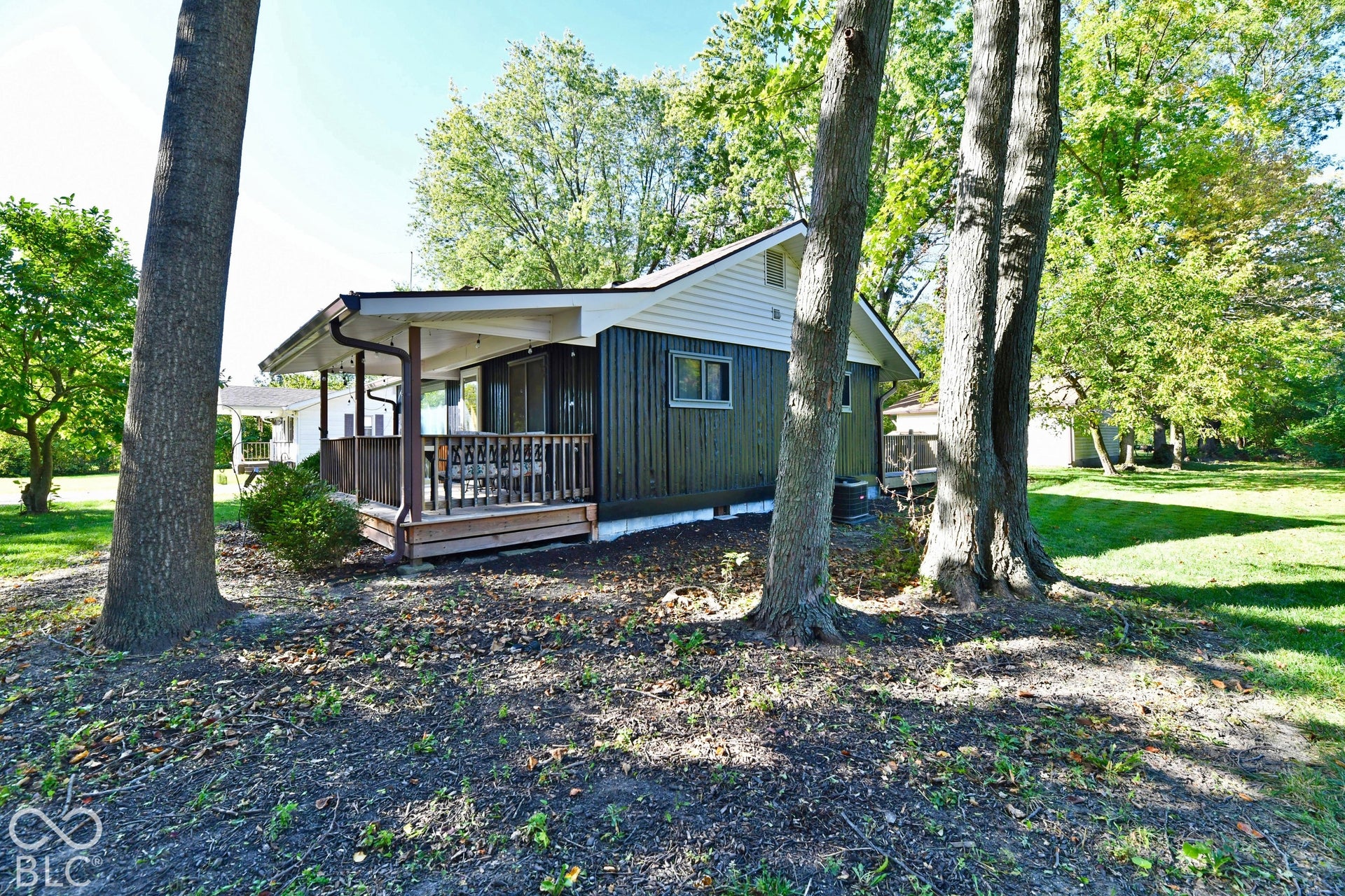 Covered porch with wood railing and columns, featuring exterior siding and a window
