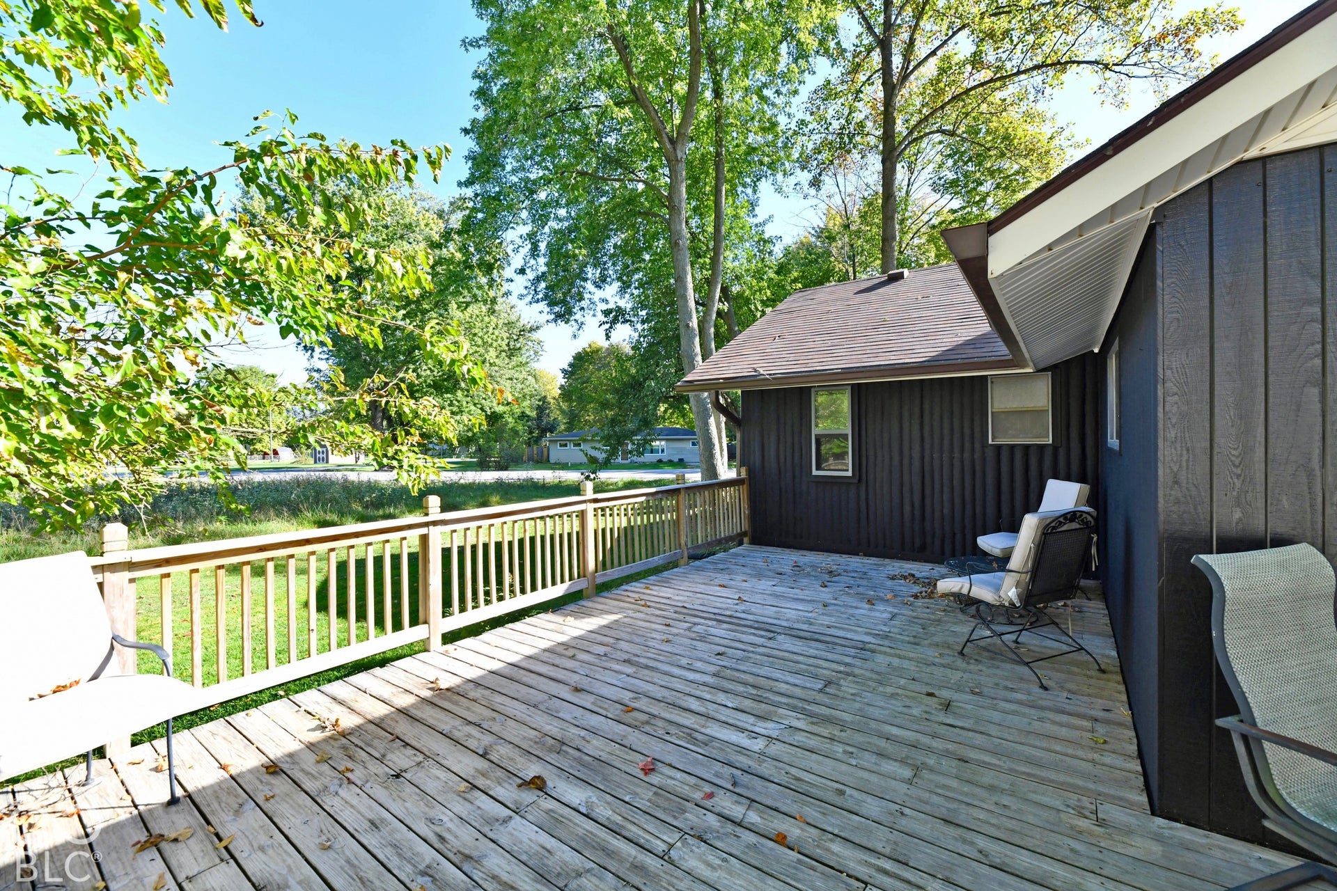 Expansive outdoor deck with a natural wood finish, wooden railing, and a dark-colored exterior siding