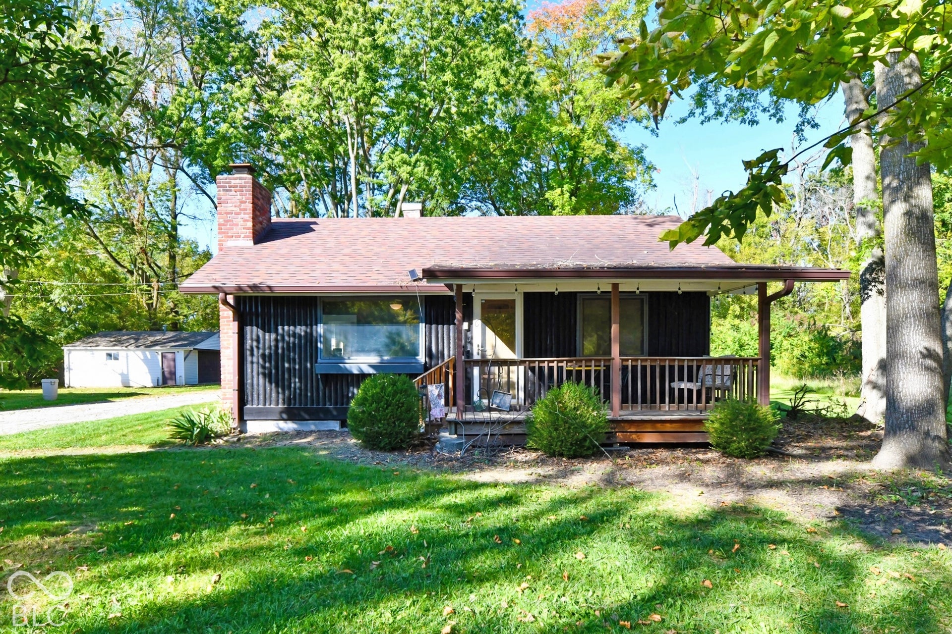 Exterior featuring a covered porch, wood plank decking, and a brick chimney