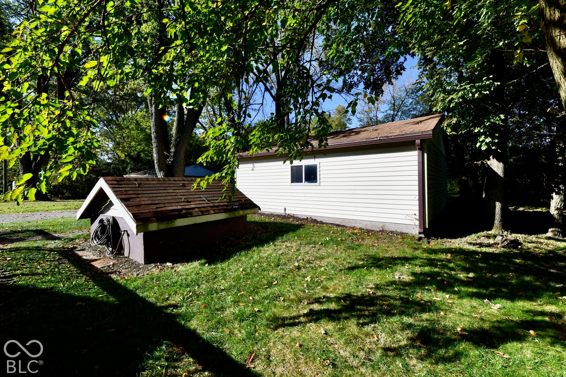 Detached outbuilding with light-colored siding and a single window