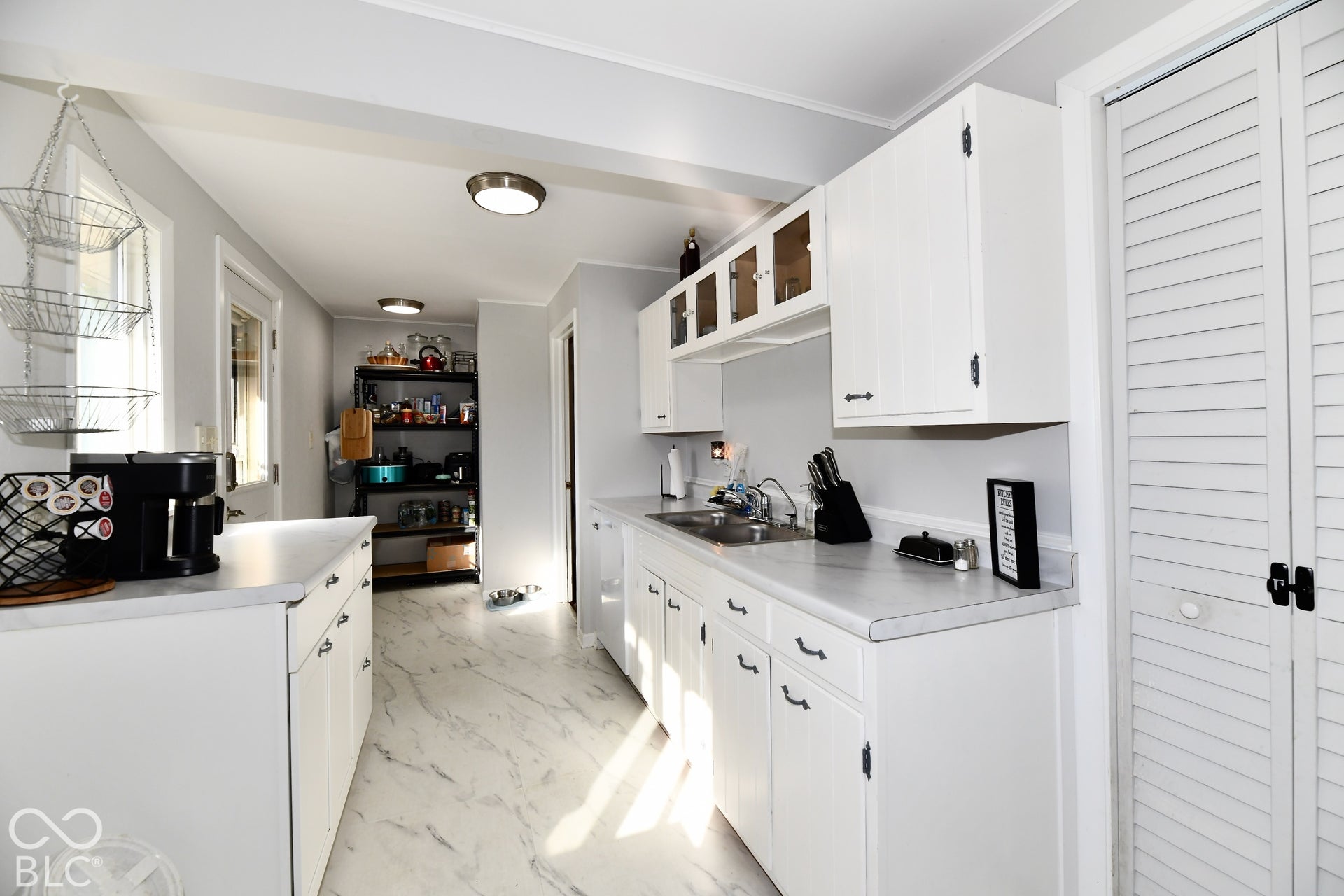 White cabinetry with matte black hardware, white countertops, and a stainless steel sink