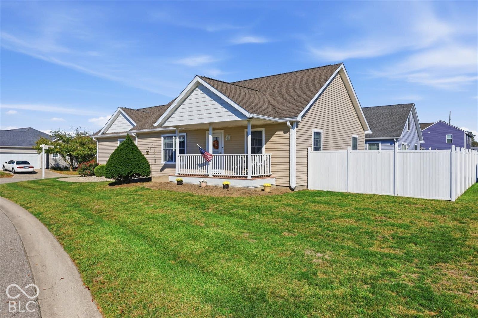Siding exterior with a covered front porch featuring white railings, a front-facing gable, and a white picket fence enclosing the backyard