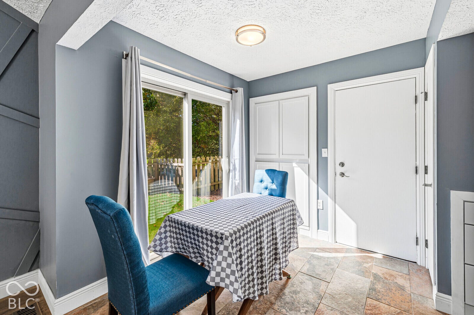 Sliding glass door, paneled accent wall, white built-in cabinetry, and tile flooring