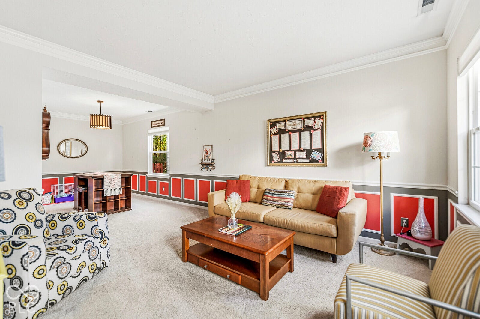 Spacious living area featuring decorative wainscoting, crown molding, neutral wall-to-wall carpeting, and multi-pane windows