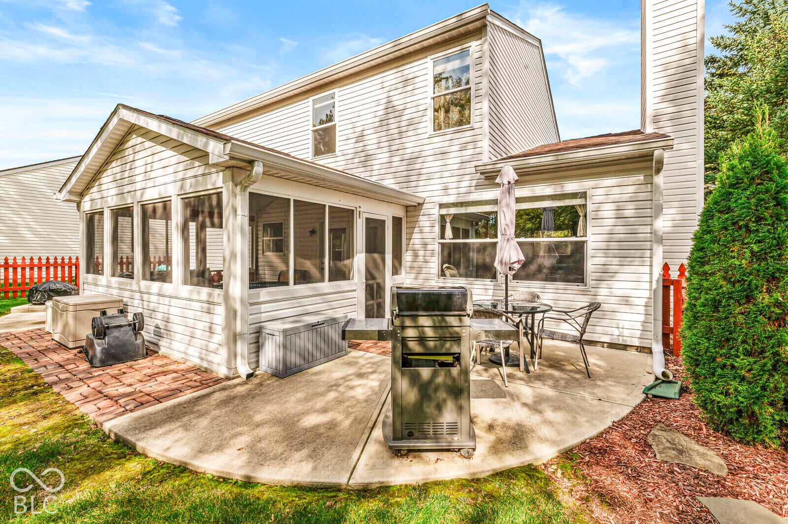 Exterior featuring vinyl siding, a screened-in porch, a concrete patio, brick hardscaping, and a chimney