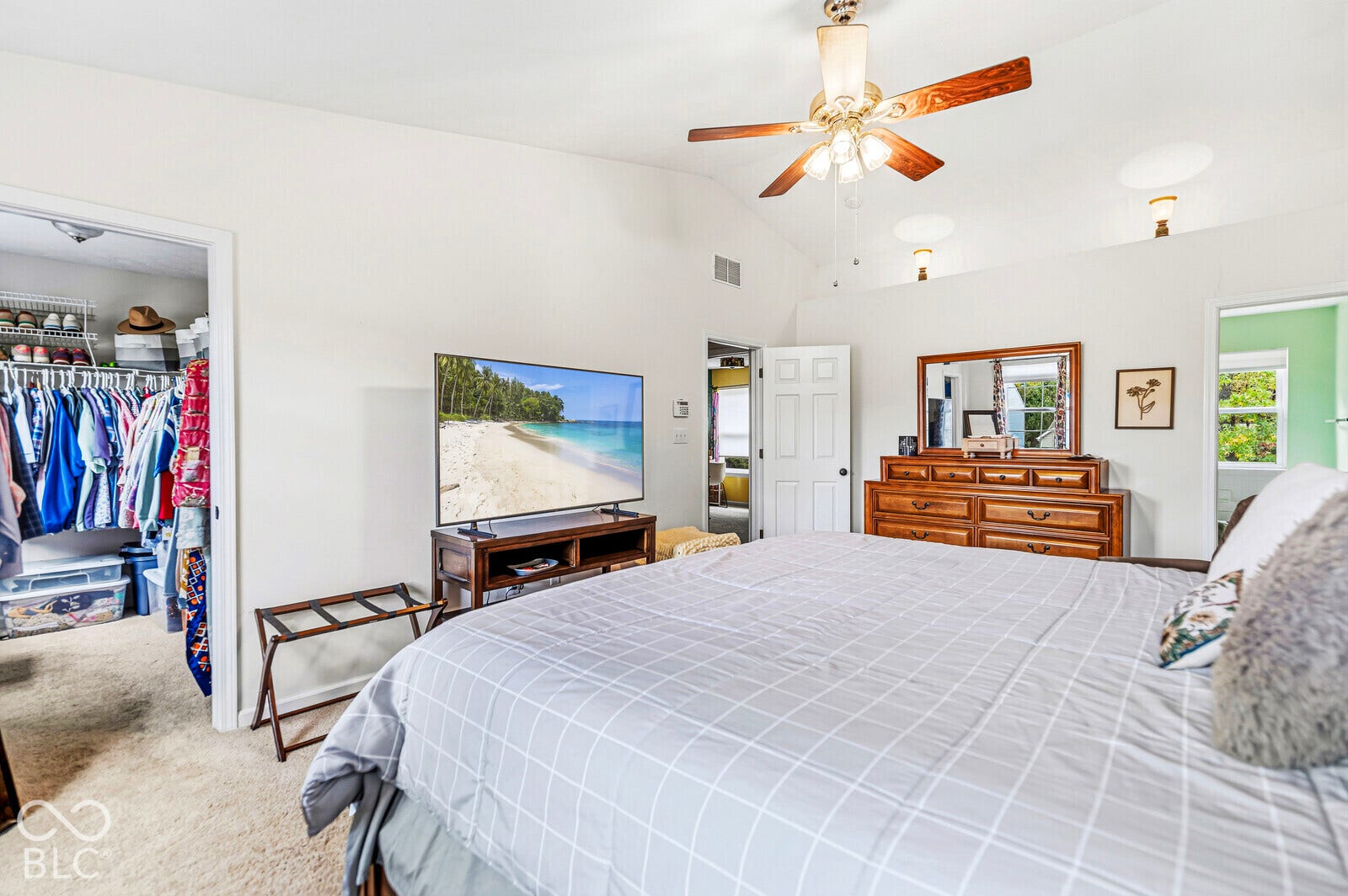 Vaulted ceilings, carpeted flooring, built-in closet shelving, and a ceiling fan with integrated lighting