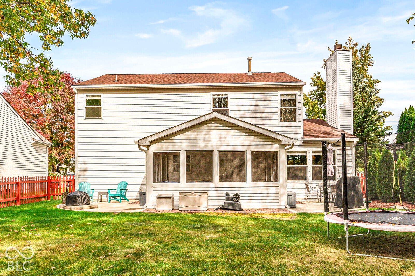 Exterior rear elevation featuring white horizontal siding, a screen-enclosed patio, a tall exterior chimney, and a concrete patio