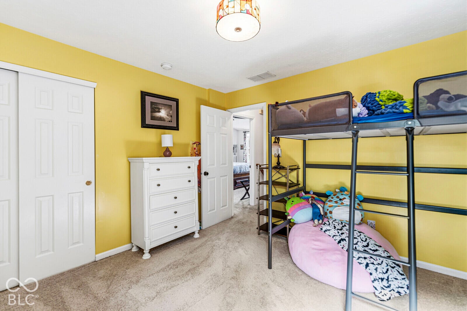 Interior room featuring wall-to-wall carpeting, sliding closet doors, a six-panel door, and a decorative flush-mount ceiling fixture