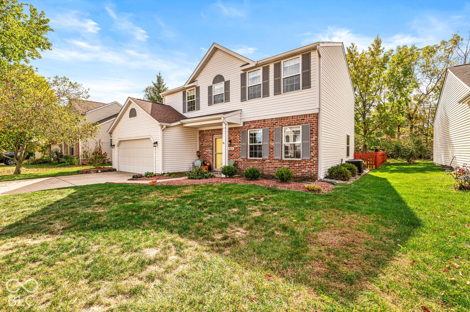 Two-story residence featuring a combination of light vinyl siding and brick veneer, a two-car attached garage, and multi-paned windows with decorative shutters