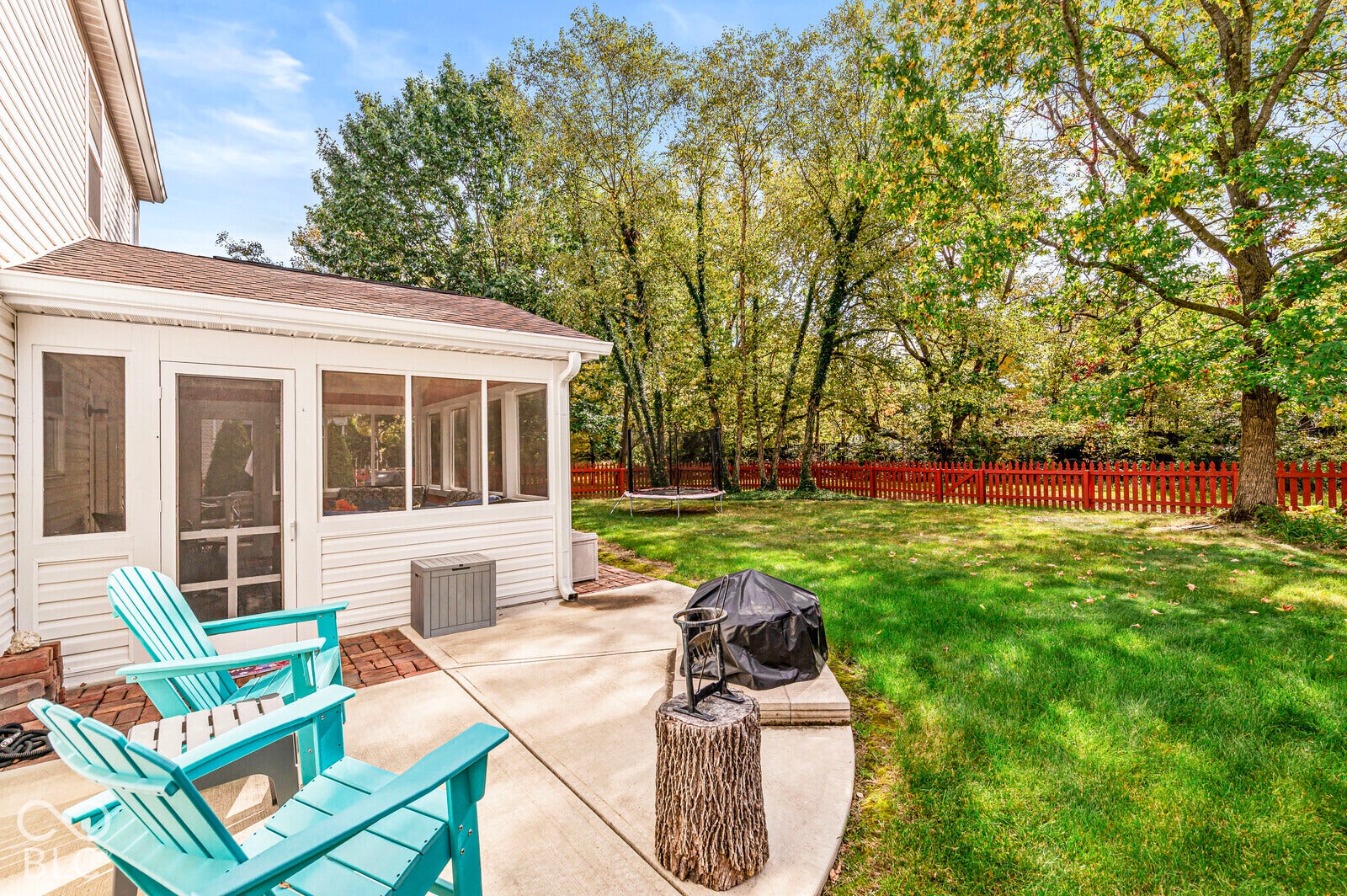 Screened-in porch with white siding, concrete patio, grass lawn, and red picket fence