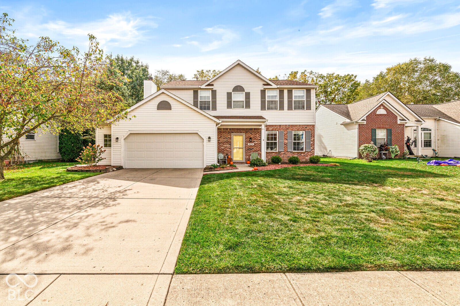 Two-story residence featuring light-toned horizontal siding, a multi-textured brick facade, attached two-car garage, and manicured front lawn