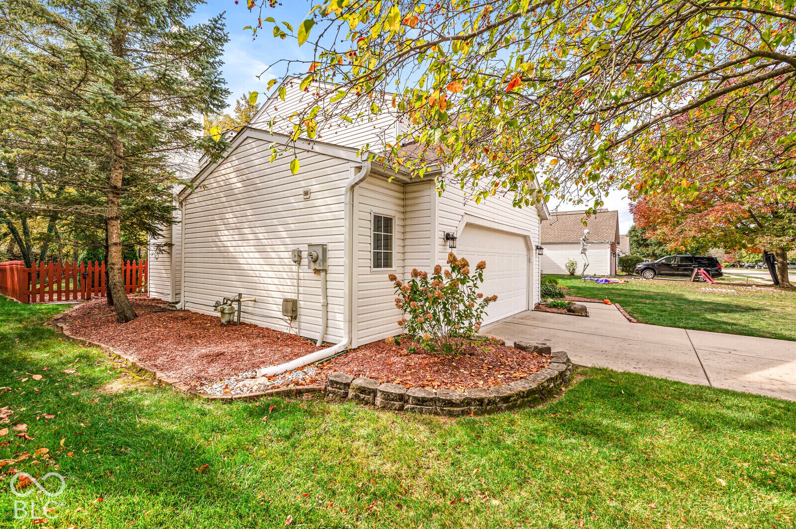 Exterior featuring white horizontal siding, a concrete driveway, a two-car garage, and a stacked-stone garden bed border