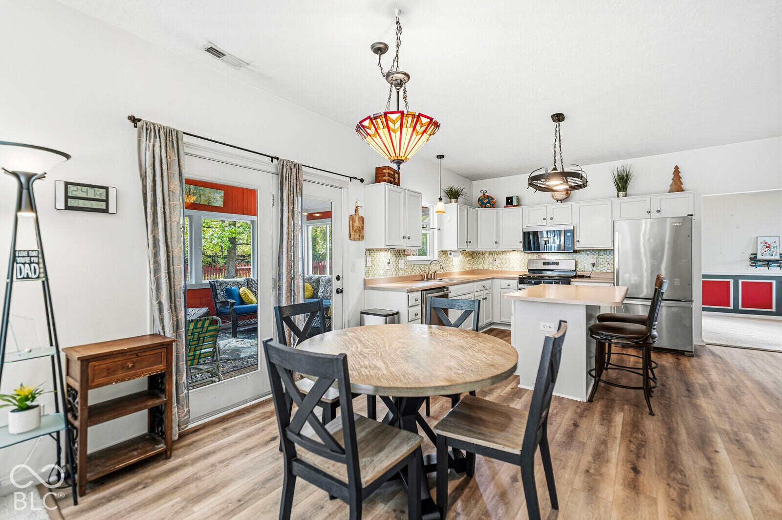 Kitchen featuring white cabinetry, wood-finish flooring, a central island, stainless steel appliances, and decorative hanging light fixtures
