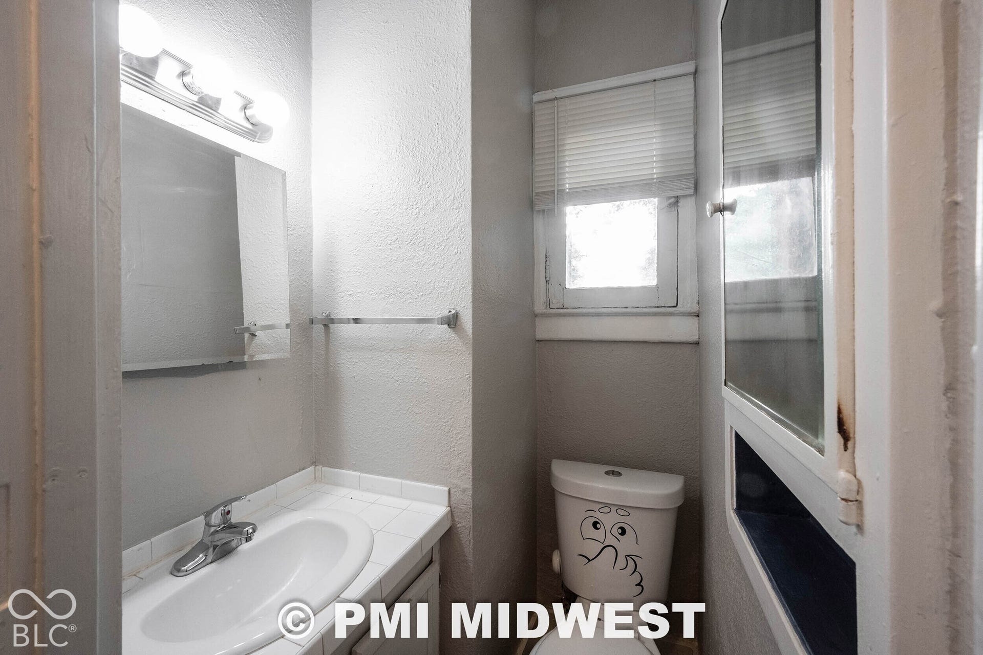 Vanity with an integrated sink and chrome faucet, wall-mounted mirror, and overhead tri-bulb light fixture