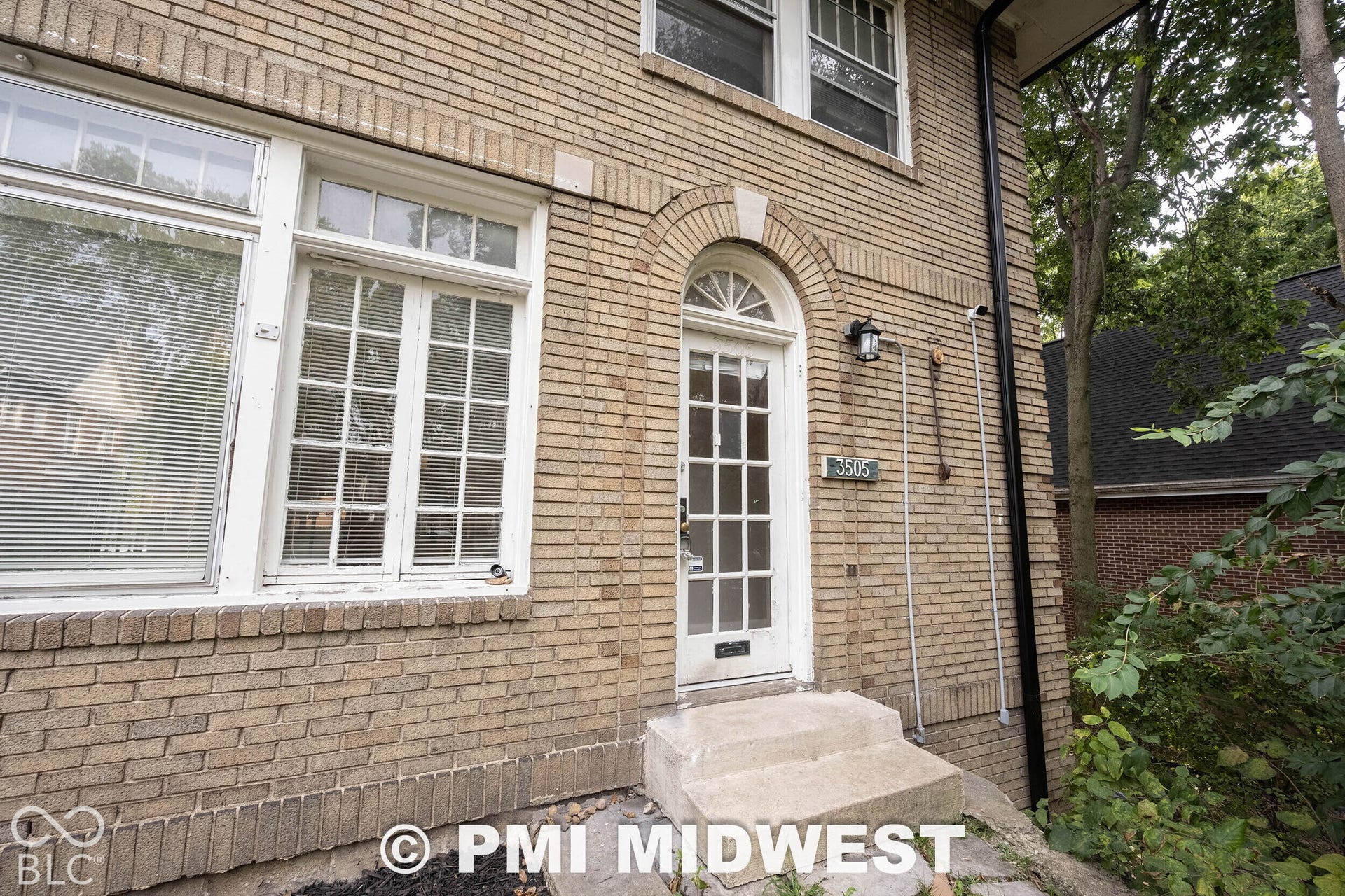 Brick exterior with an arched entryway, transom window, and multi-pane windows
