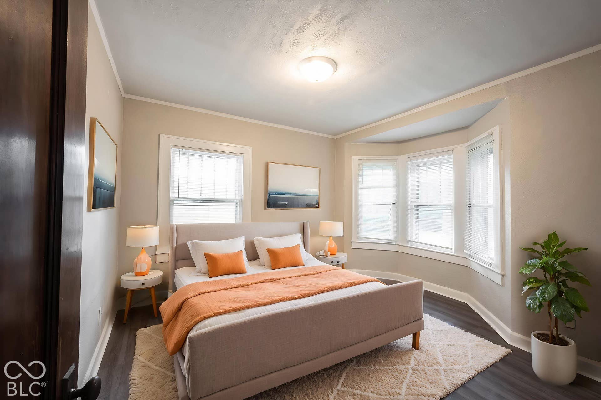 Room with wood-finish flooring, a three-panel bay window, and light neutral wall paint