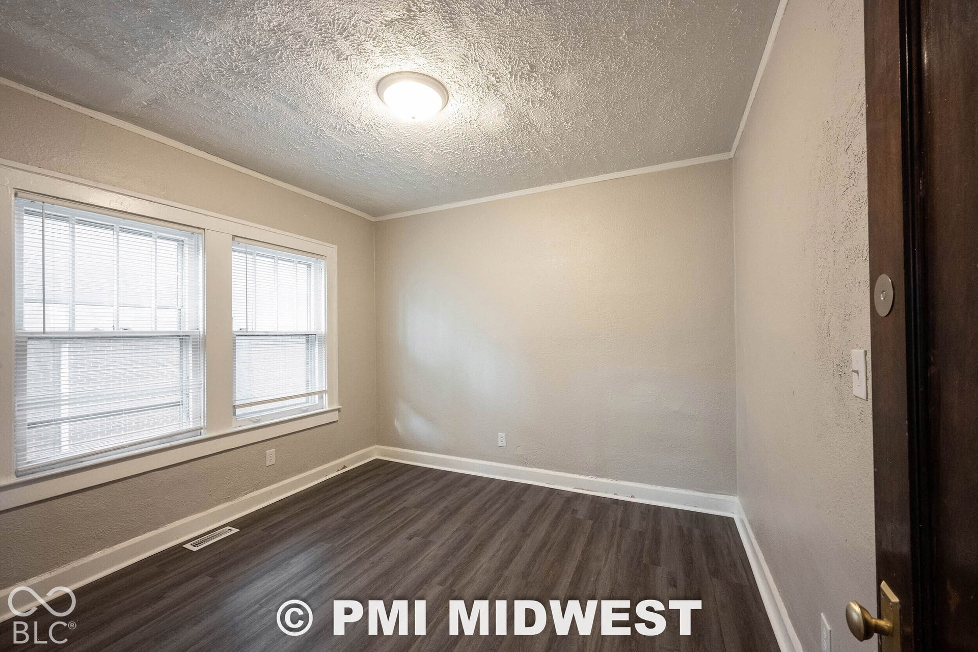 Recessed ceiling light fixture, wood-finish flooring, and two windows with blinds