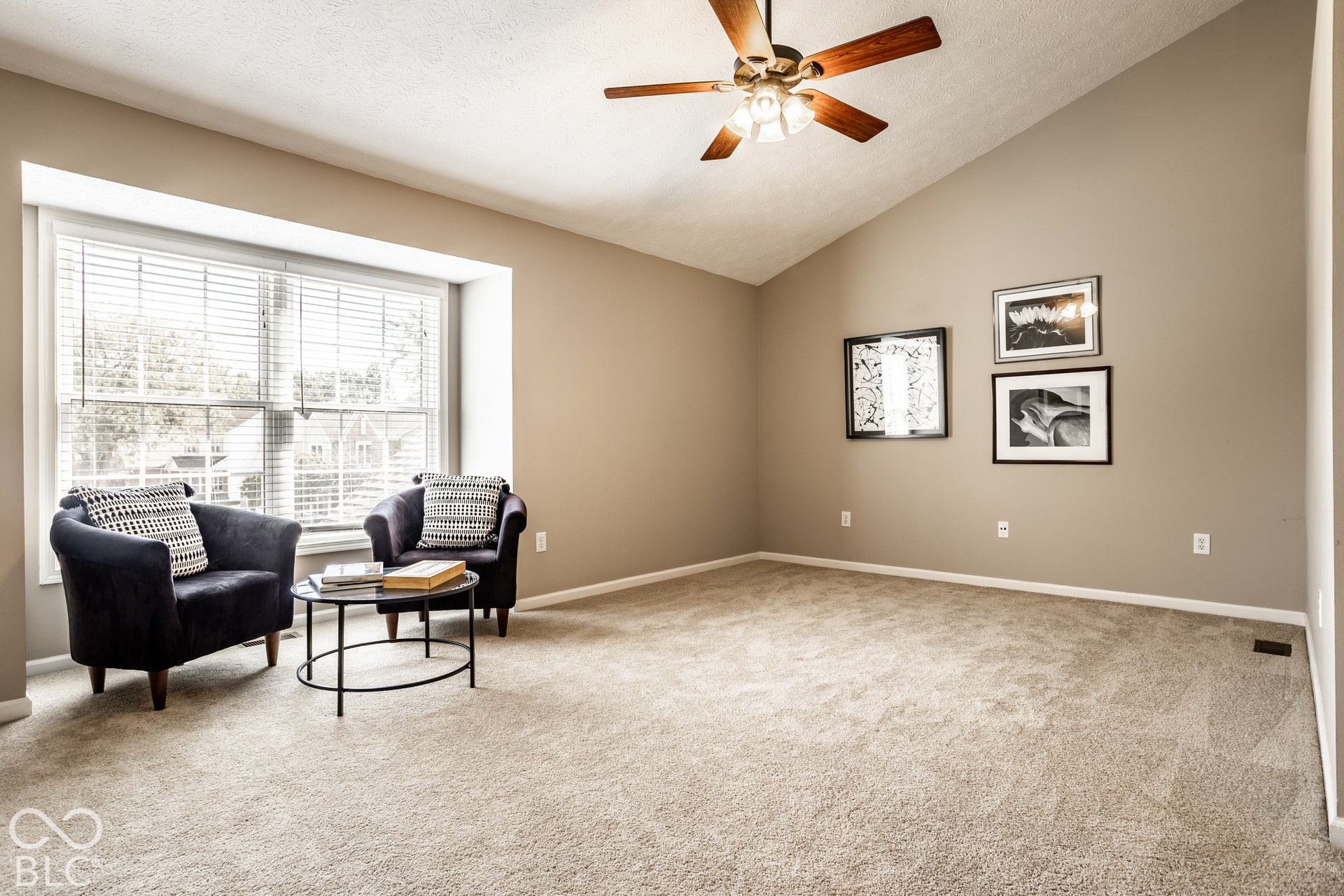 Vaulted ceiling with a ceiling fan, bay window, and neutral carpeting