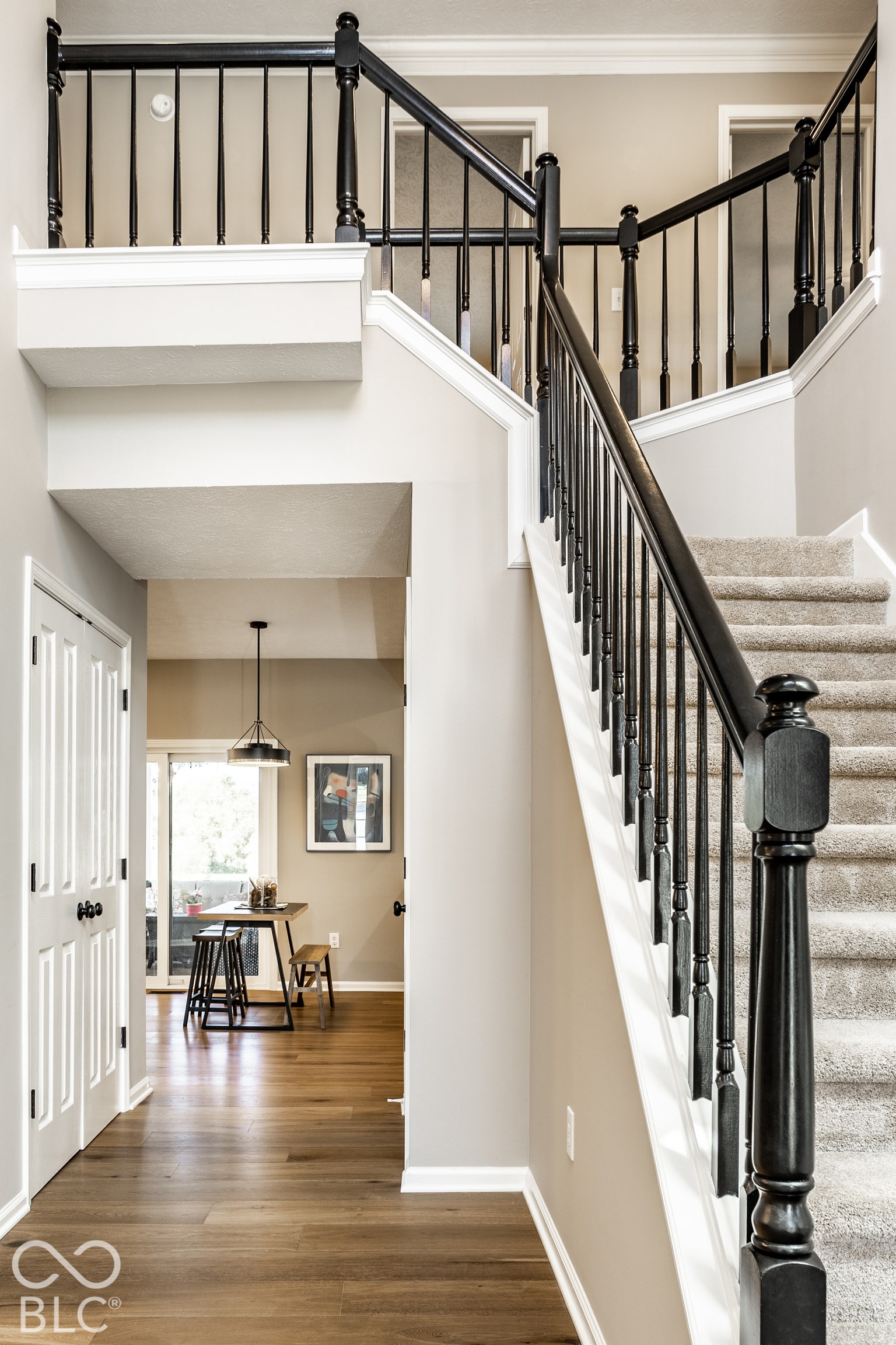 Staircase with black balusters and carpeted treads, wood-finish flooring