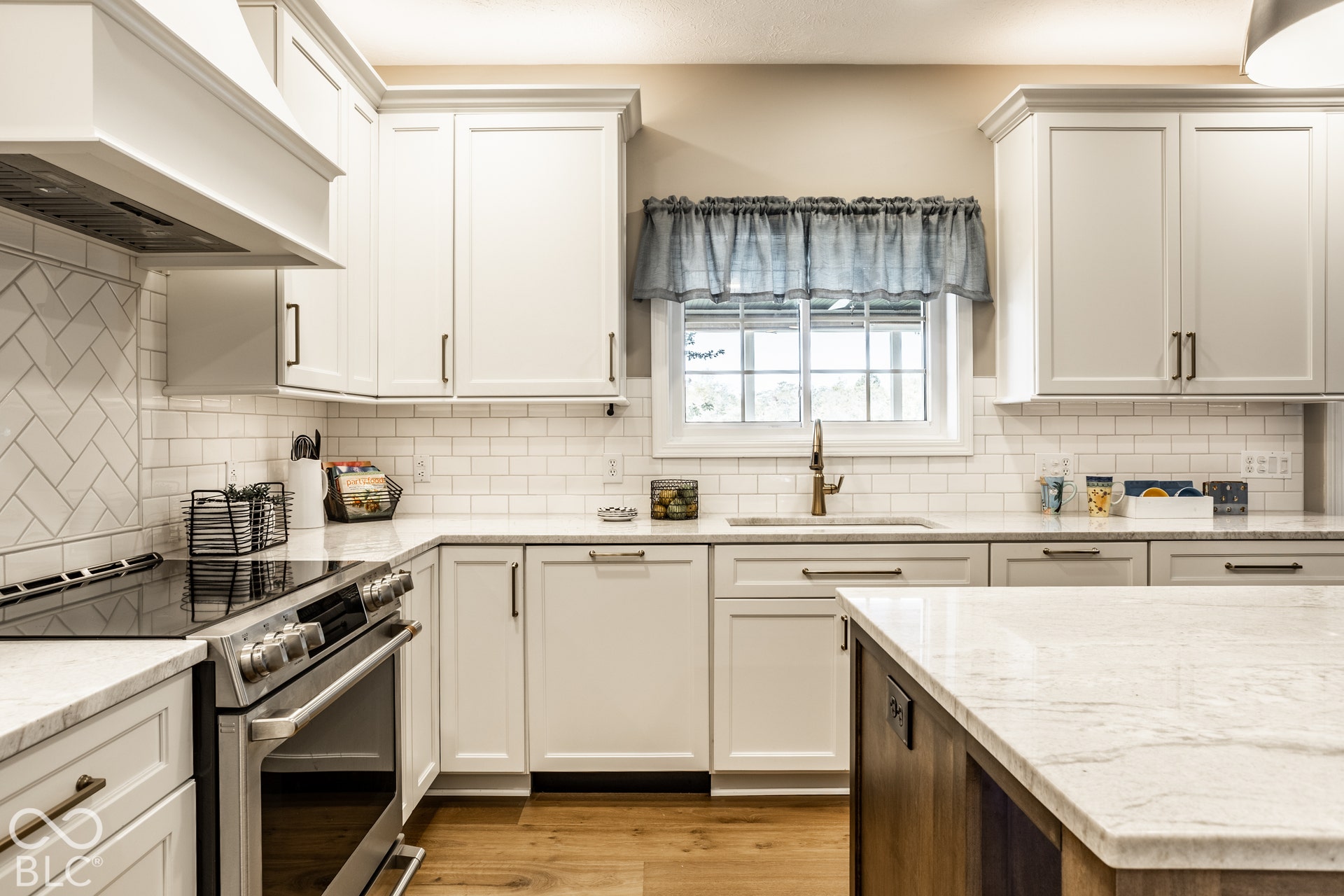 White shaker cabinetry, light-toned countertops, wood-finish flooring, subway tile backsplash, and stainless steel appliances
