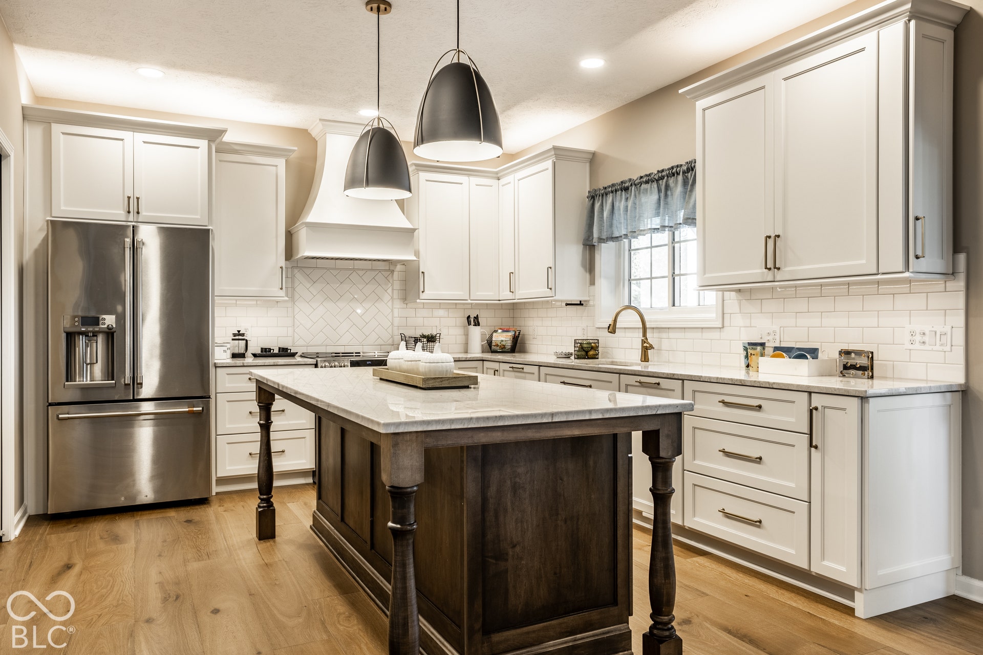 Kitchen featuring wood-finish flooring, white cabinetry, a wood-finish island with a stone countertop, a tile backsplash, and stainless steel appliances