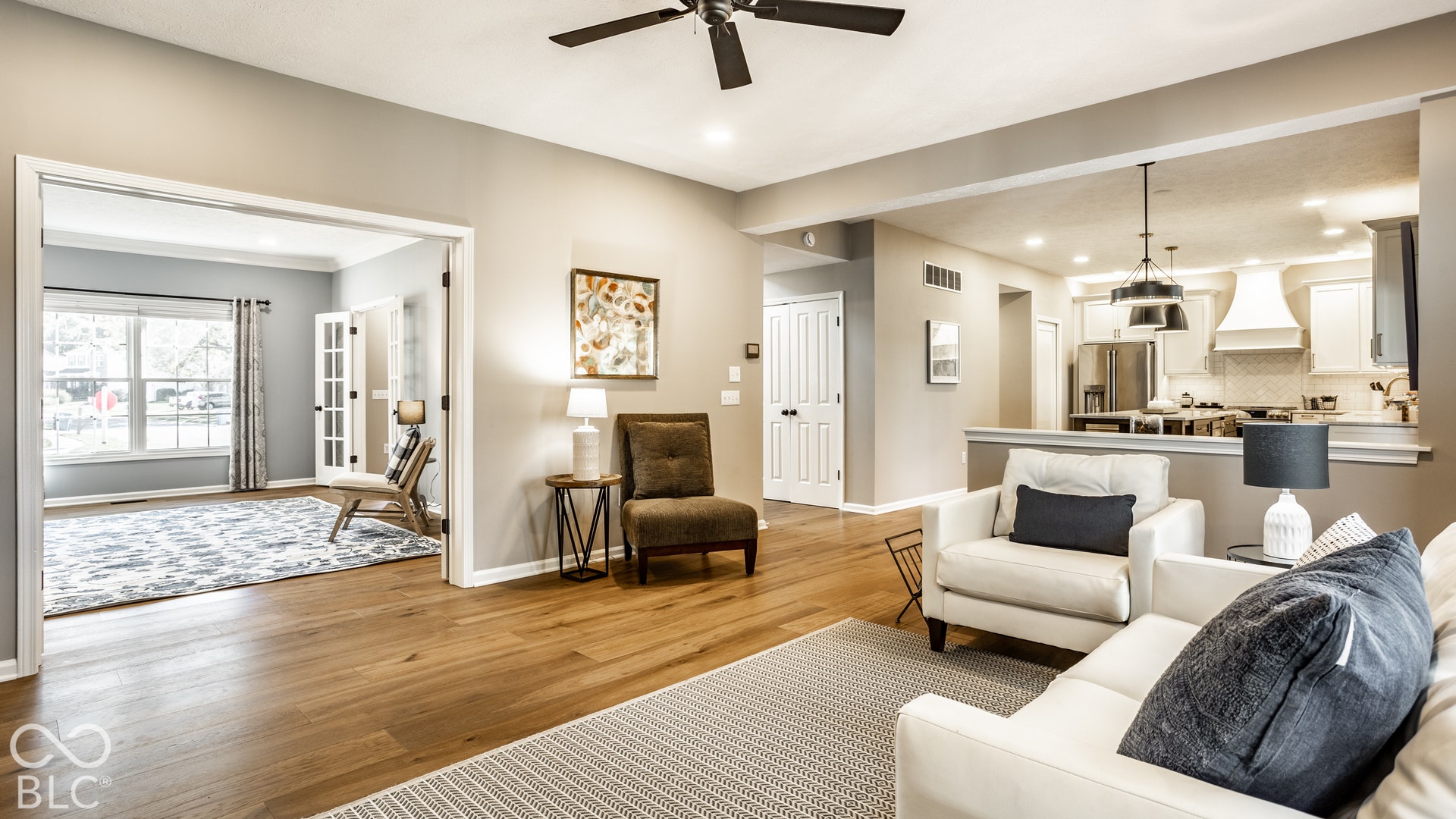 Wood-finish flooring throughout, featuring a kitchen with white cabinetry, stainless steel appliances, and dual pendant lighting