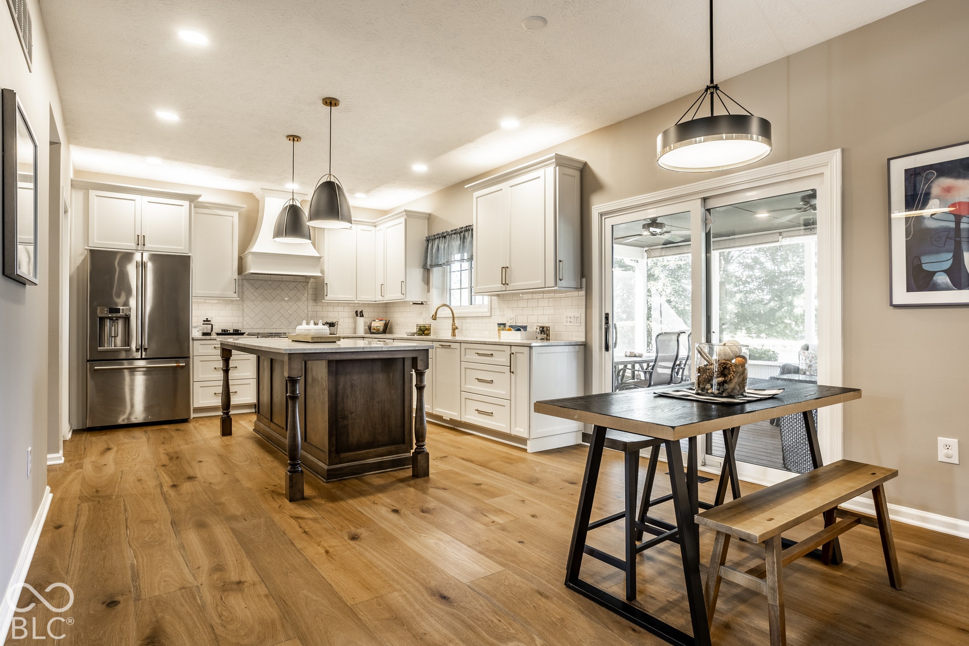 Gourmet kitchen with wood-finish flooring, two-tone cabinetry, stainless steel appliances, and a custom island