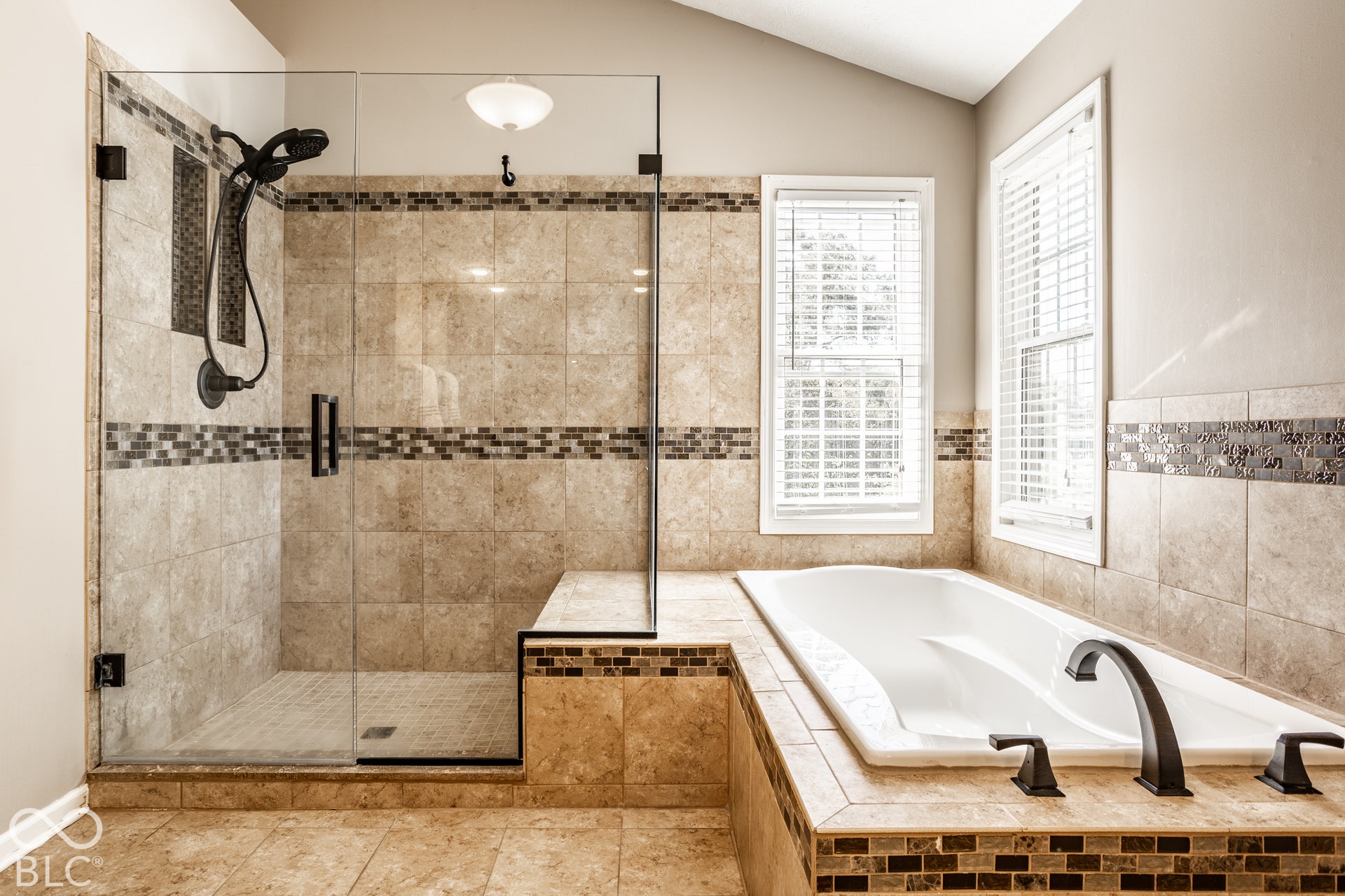Walk-in shower with clear glass enclosure, built-in bench, and bronze fixtures
