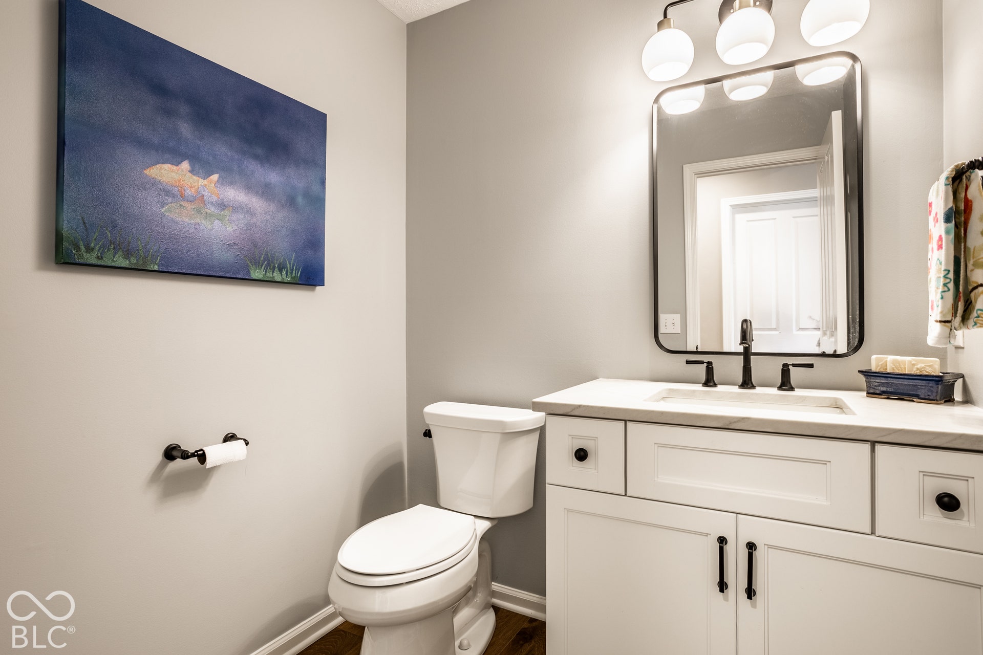White vanity with black hardware, integrated sink, and a rectangular mirror with rounded corners