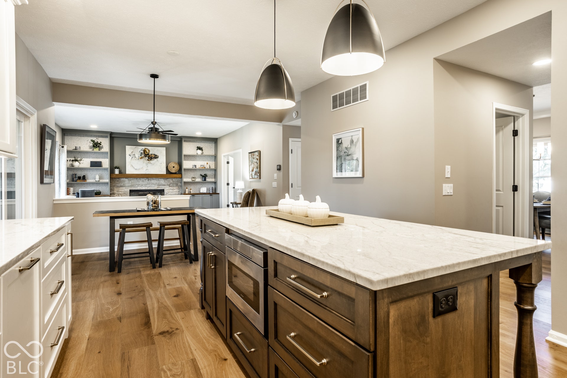 Gourmet kitchen featuring a large island with built-in microwave, wood-finish flooring, two-tone cabinetry, and pendant lighting