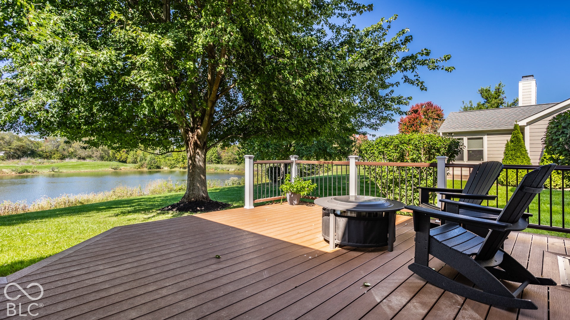 Expansive composite deck with a dark railing and a tranquil pond backdrop