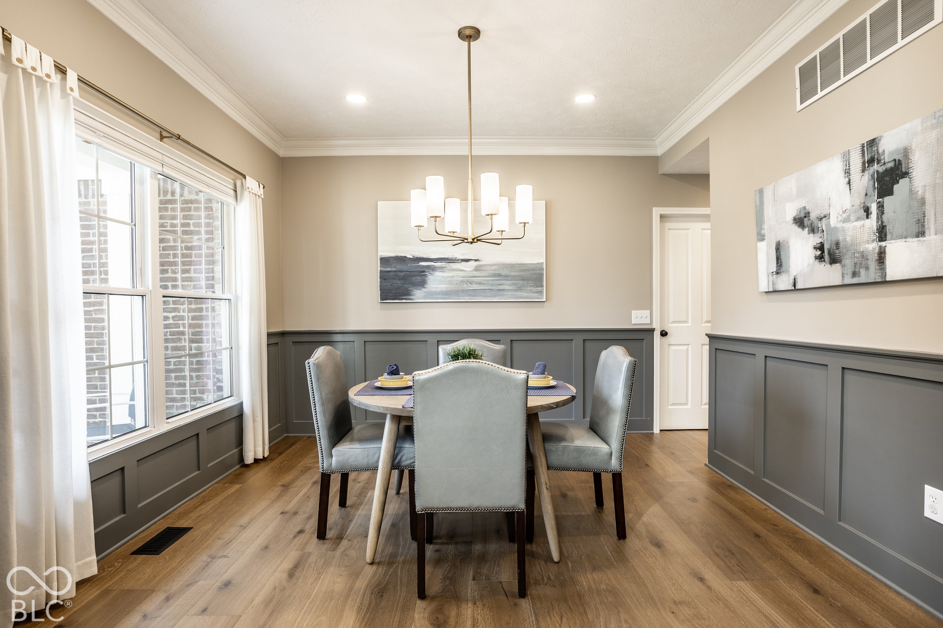 Wood-finish flooring with wainscoting, crown molding, and recessed lighting