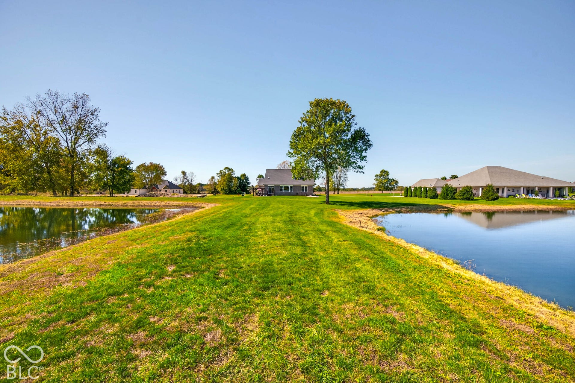 Expansive green space with two serene ponds and a distant residential structure