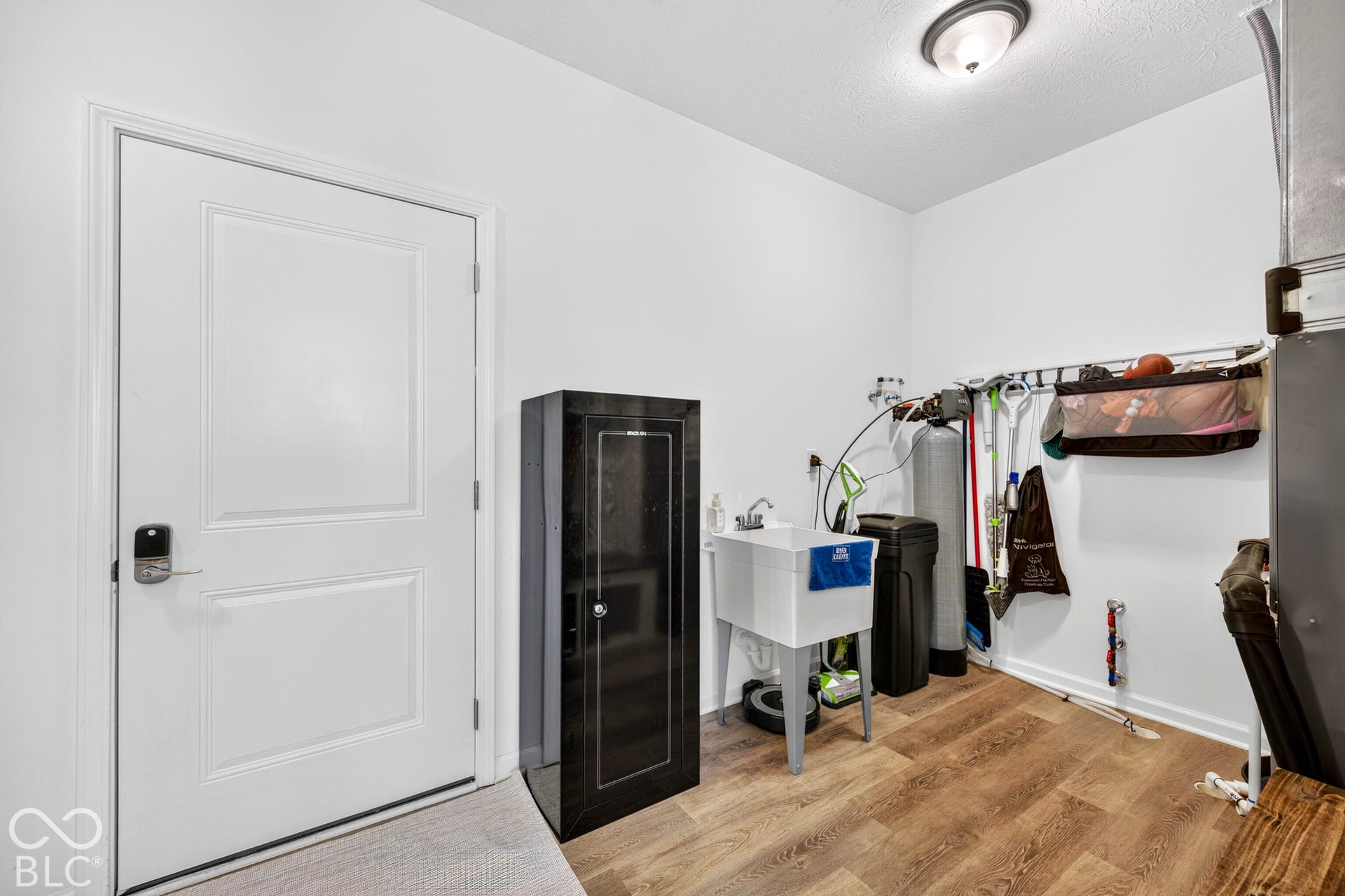 Utility room with wood-finish flooring, a utility sink, and a flush-mount ceiling light fixture