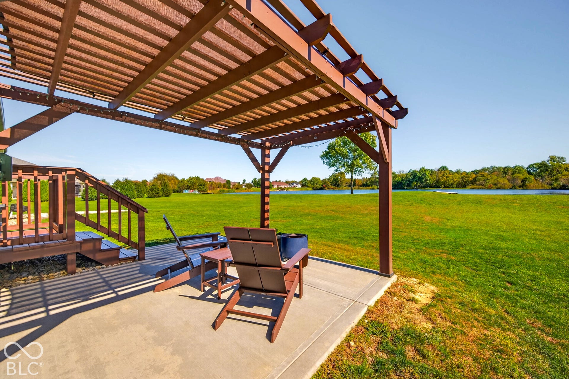 Exterior patio featuring a wooden pergola, concrete slab, and wooden deck with stairs