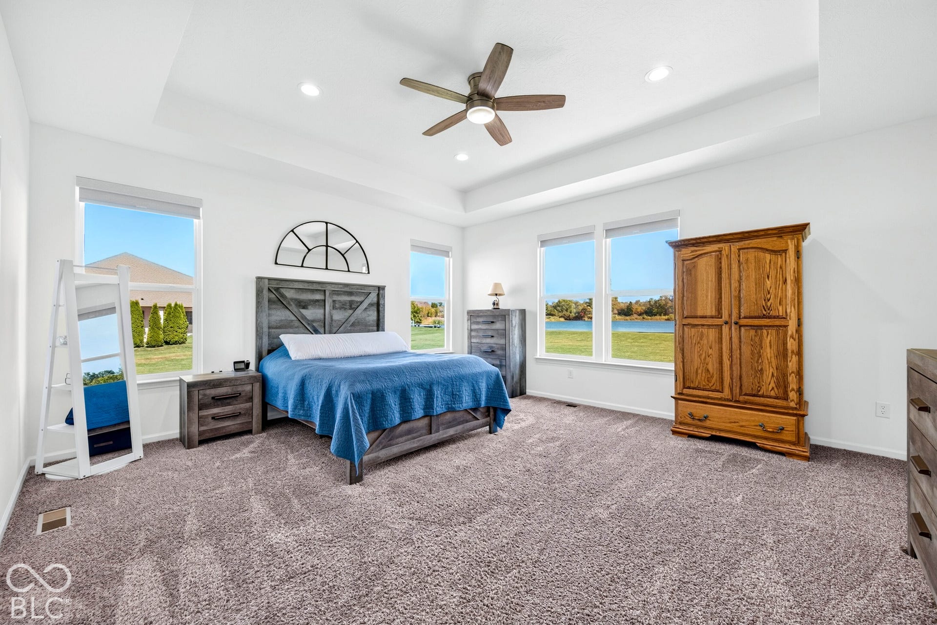 Tray ceiling with recessed lighting and a ceiling fan, multiple windows, and plush carpet flooring