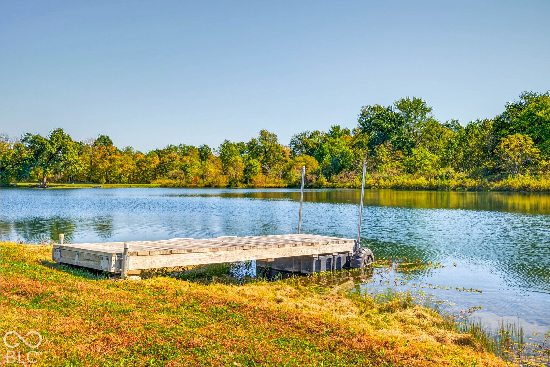 Waterfront property featuring a wooden dock, natural shoreline, and mature trees