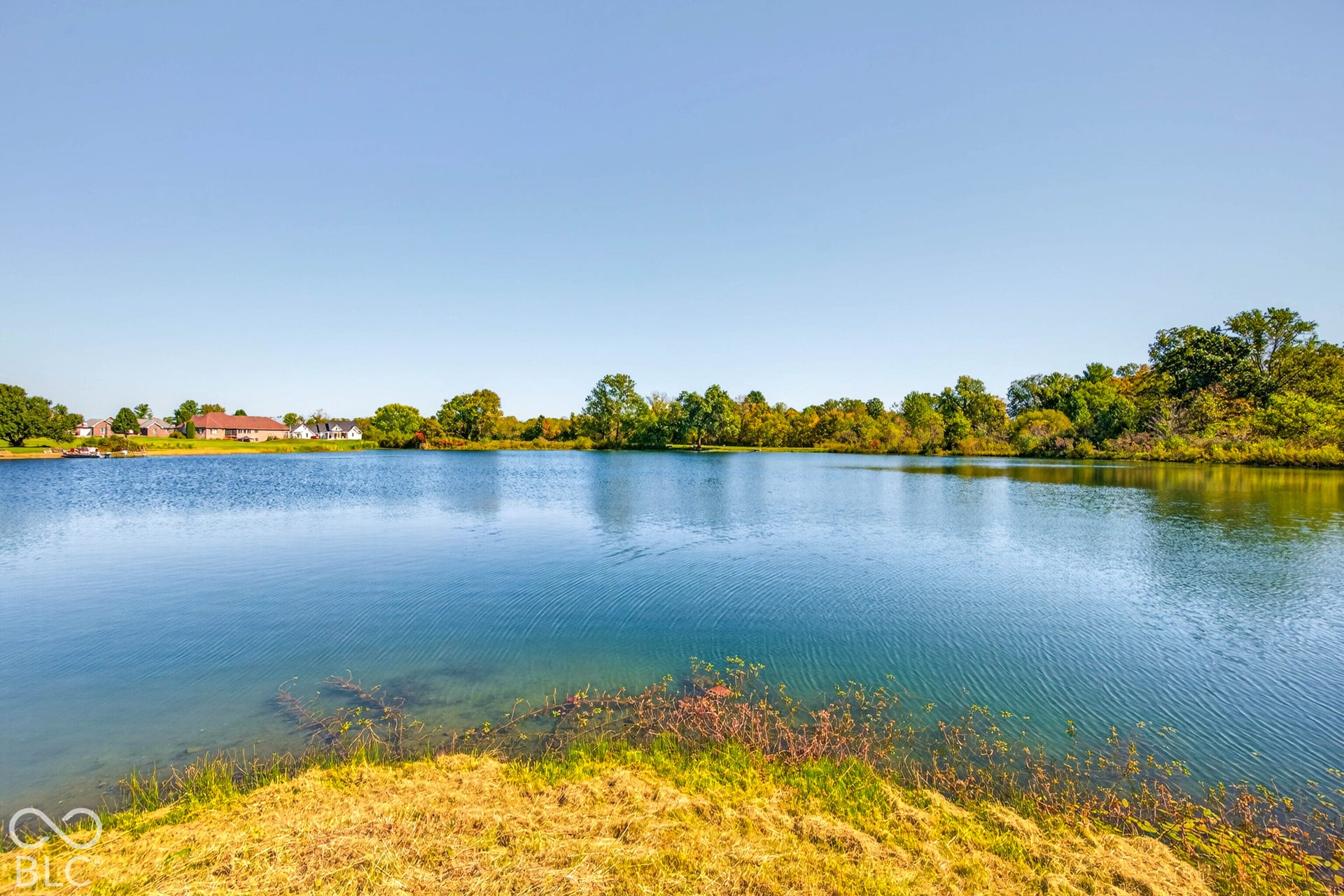 Expansive waterfront setting with clear blue water and natural vegetation along the banks