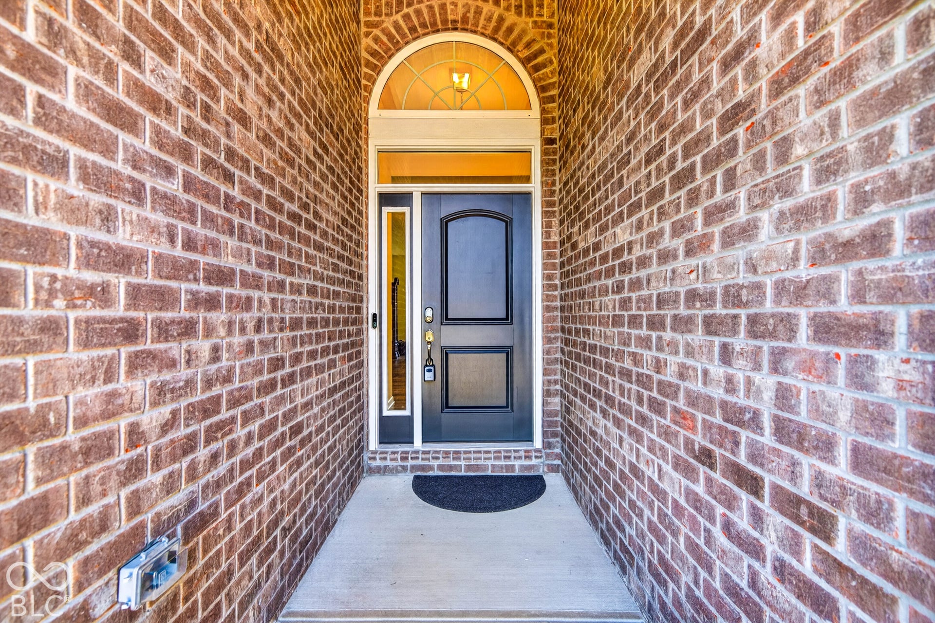 Brick exterior with an arched transom window, dark entry door, and concrete walkway