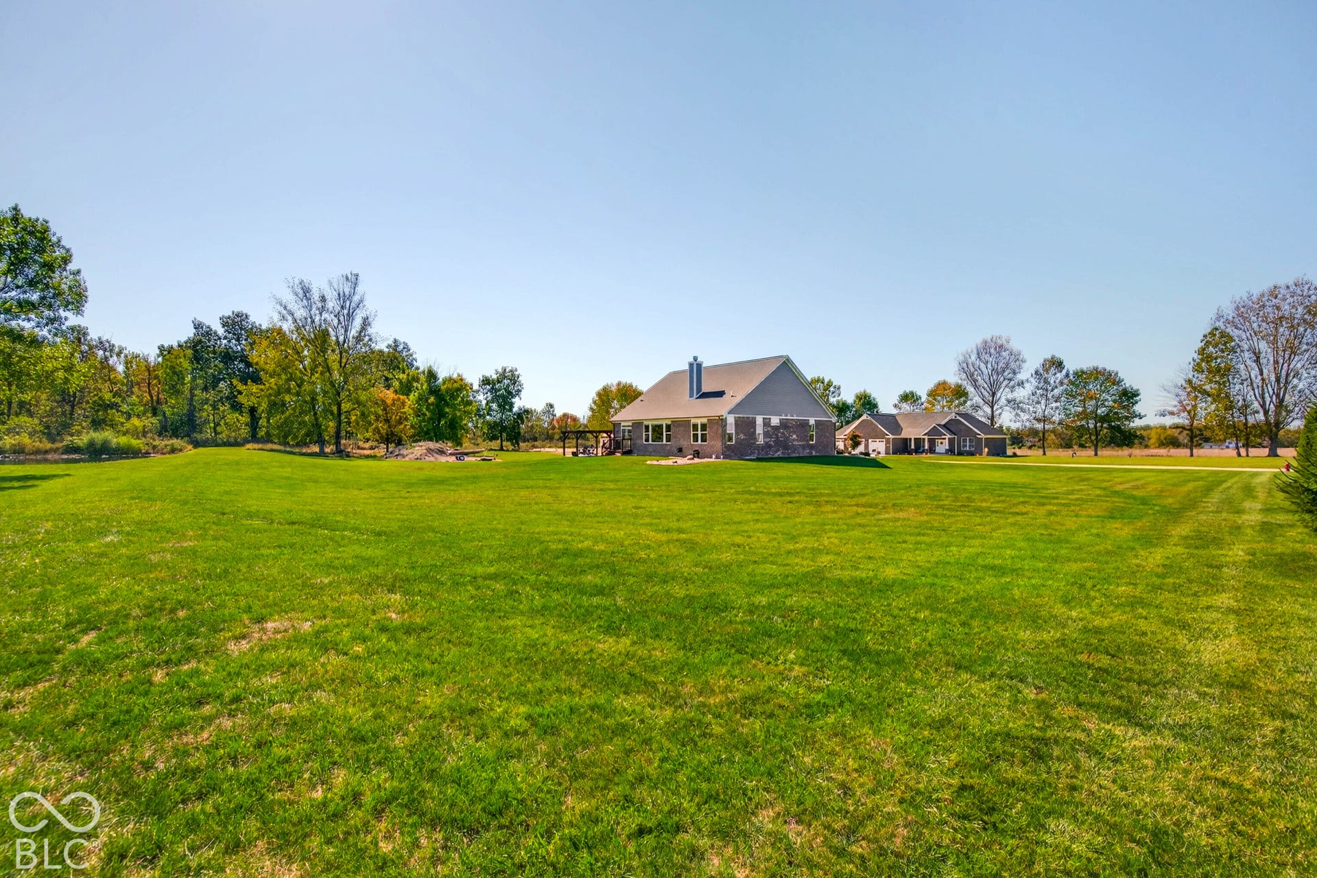 Expansive green lawn with a single-story residence featuring a gabled roof and stone exterior accents