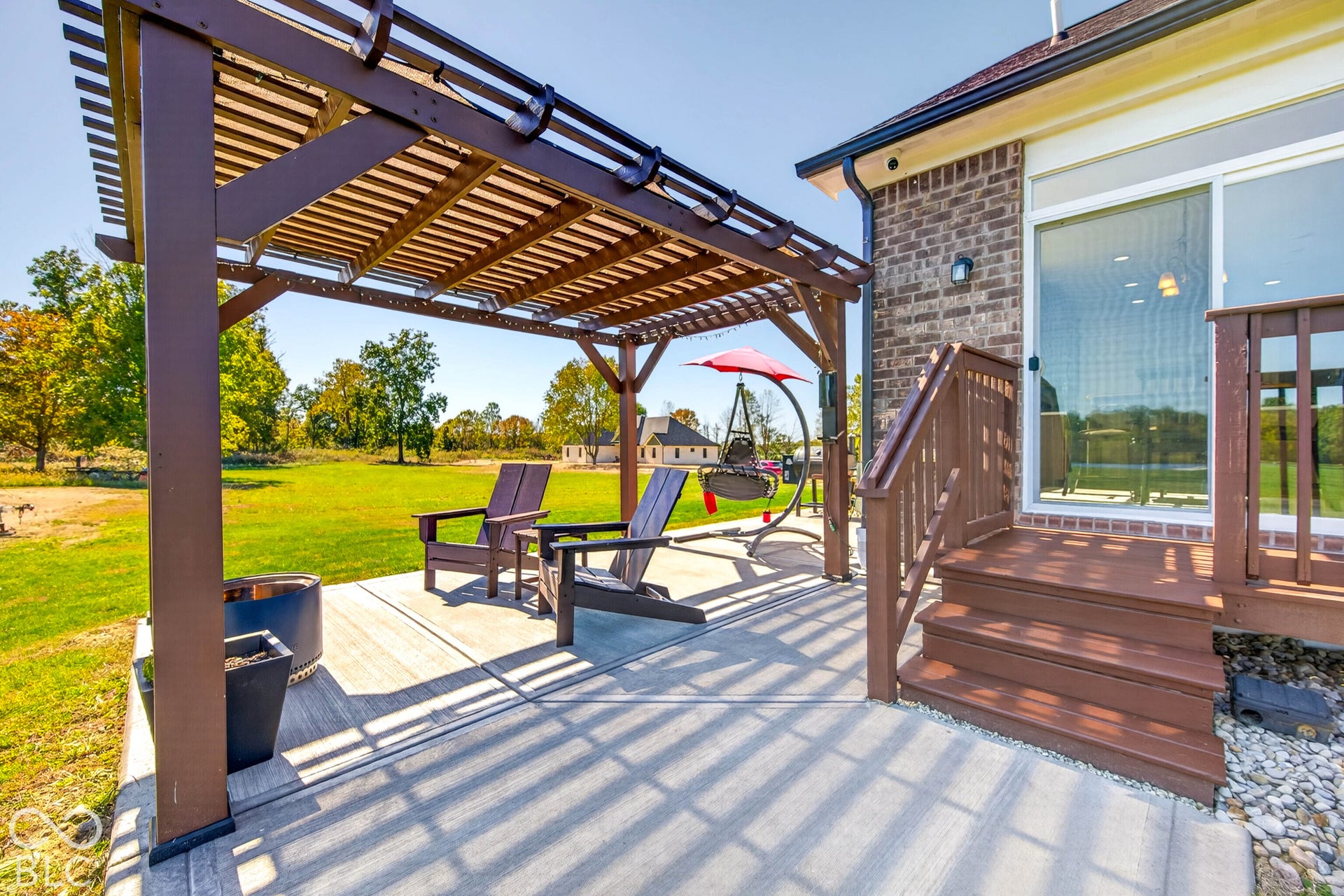 Outdoor living space featuring a wood pergola, concrete patio, and wood deck with railings