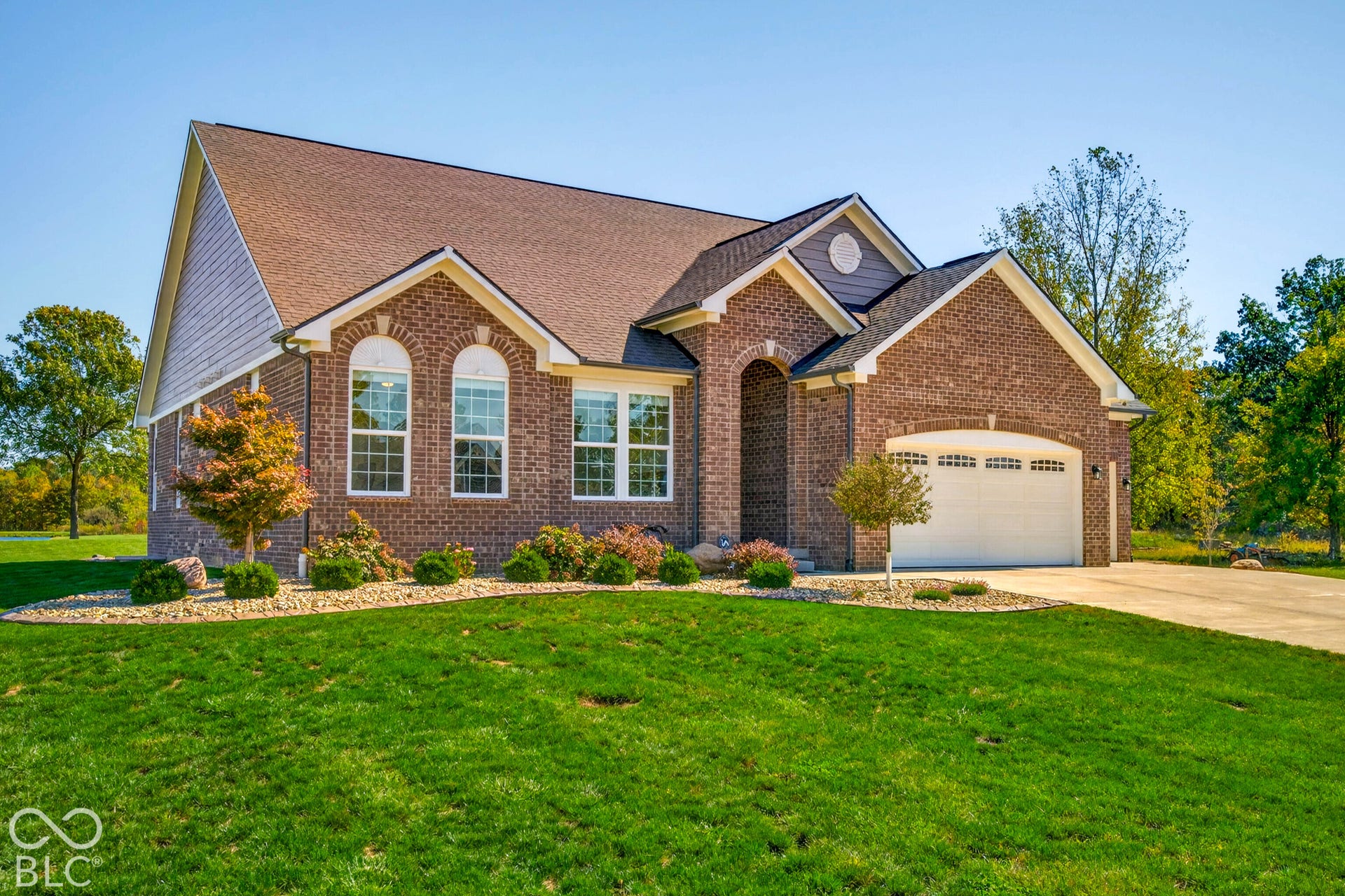 Brick exterior with an arched entryway, two-car garage, and a concrete driveway