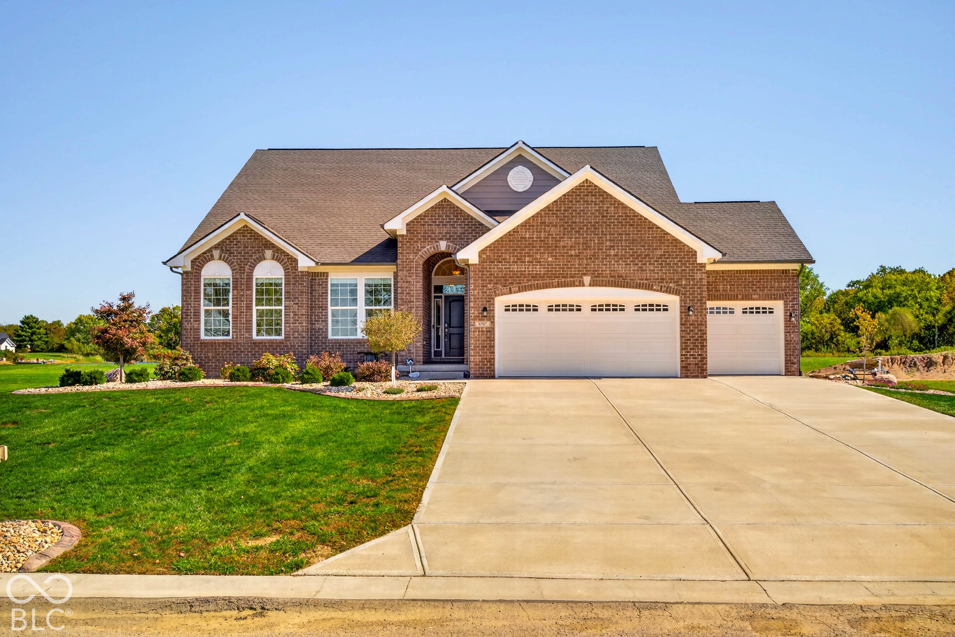 Brick exterior with arched entry, arched windows, and a two-car garage