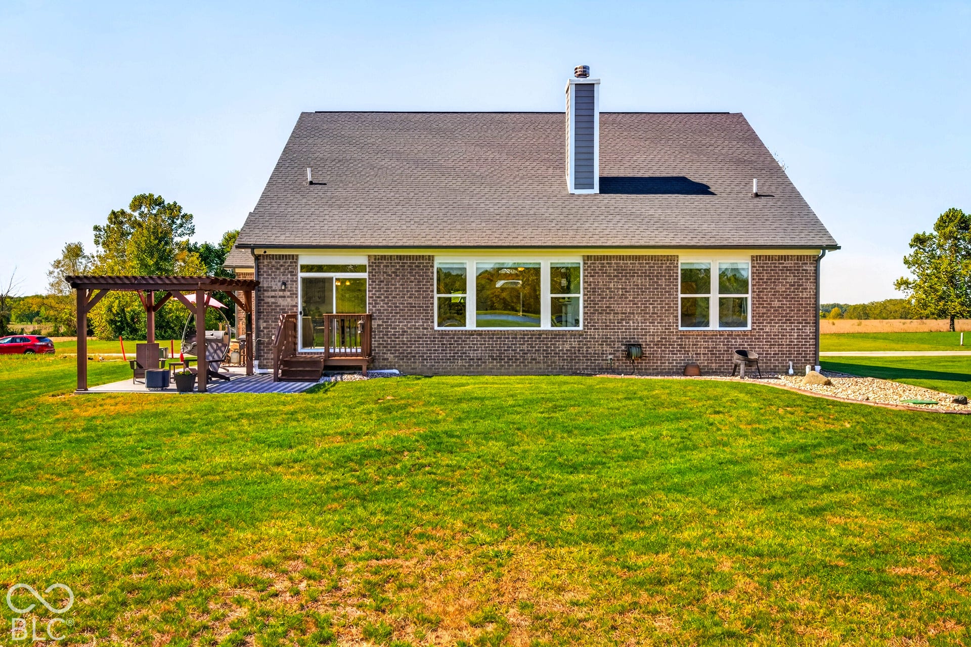 Brick exterior with multiple windows, a rear deck, and an attached pergola