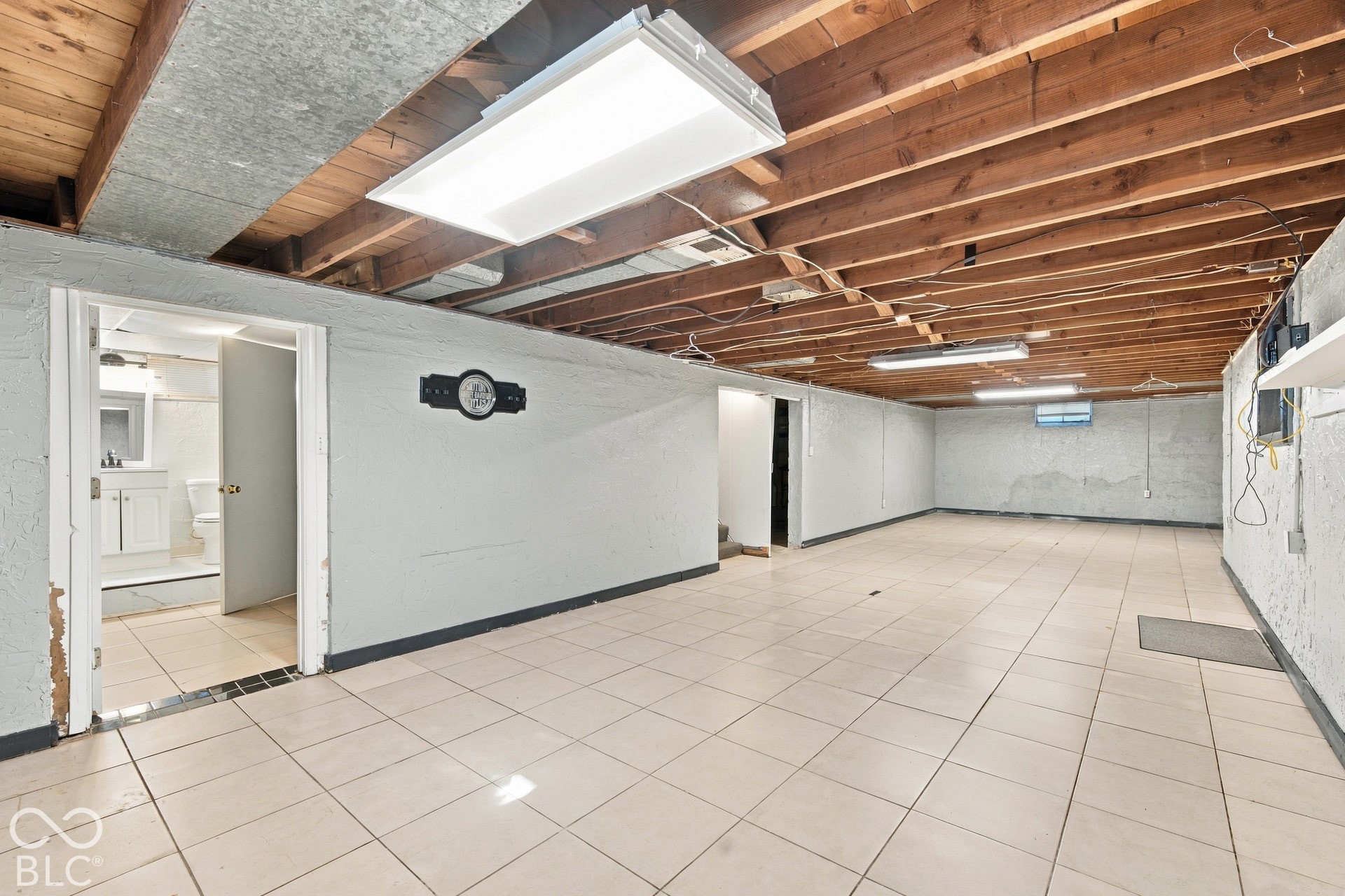 Spacious room with large format tile flooring and exposed wood beam ceiling