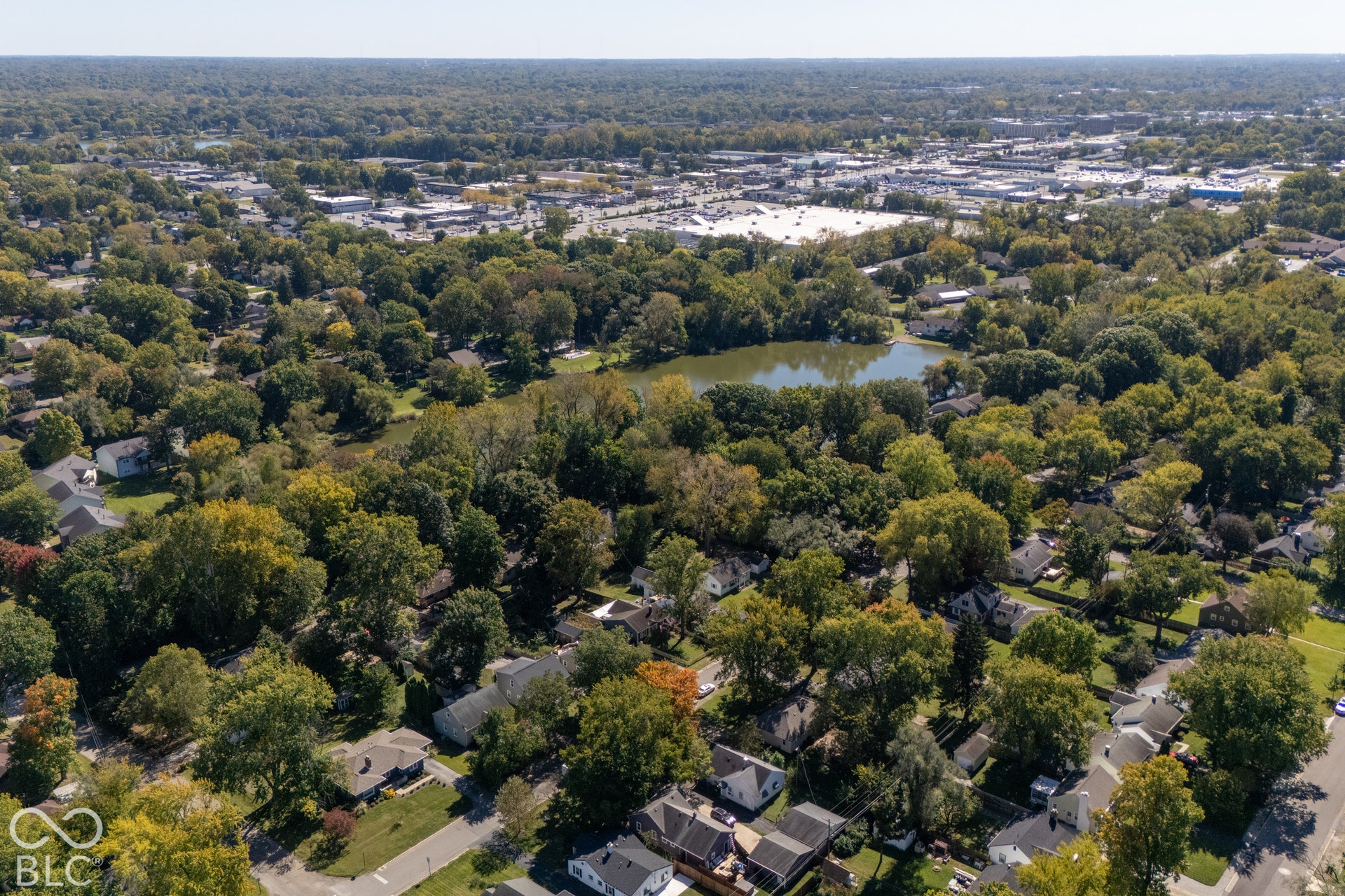 Aerial perspective showcasing a residential area, a central body of water, and abundant mature trees