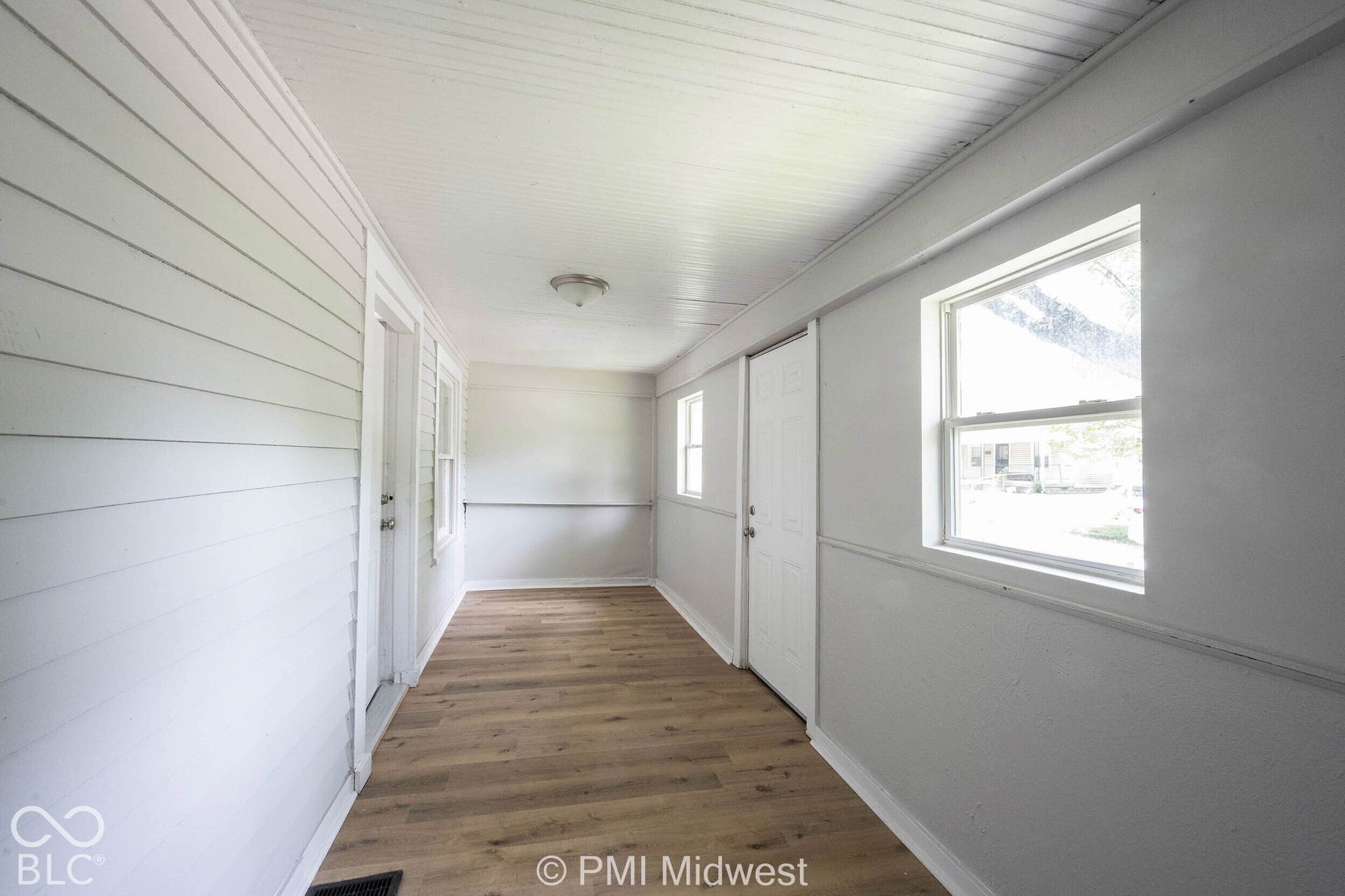 Wood-finish flooring throughout, white paneled ceiling, and multiple windows