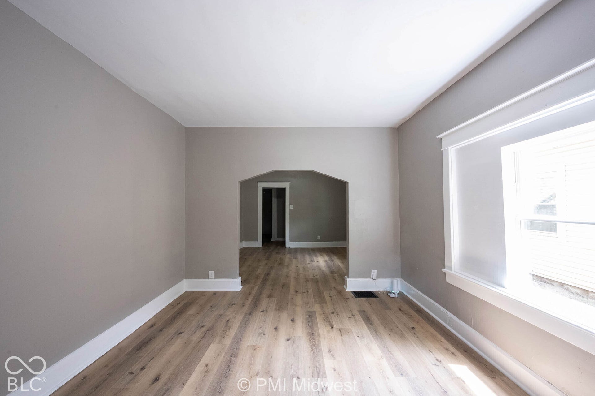 Wood-finish flooring throughout, neutral paint palette, white trim, and an arched doorway