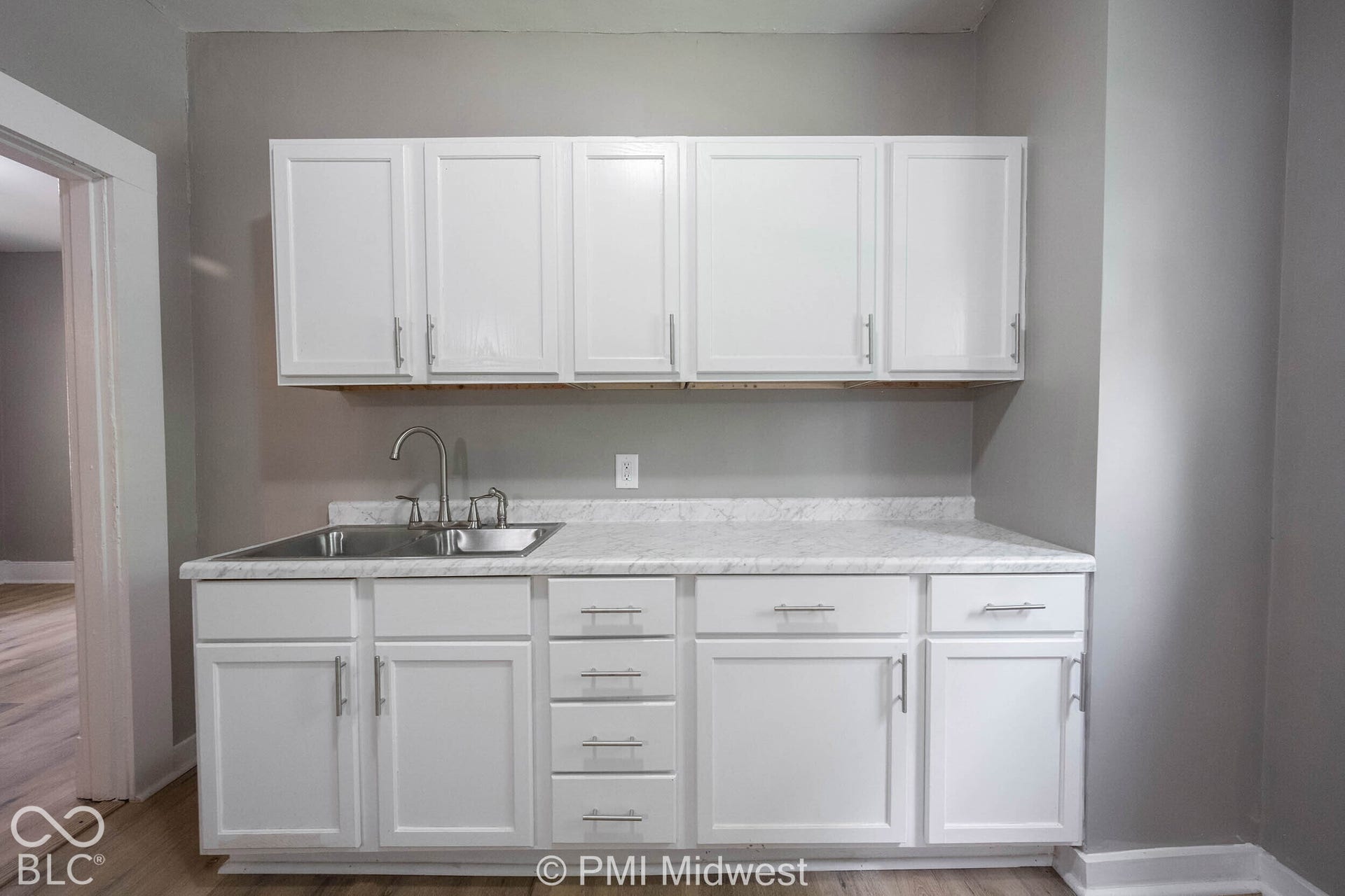 White shaker-style cabinetry with chrome hardware, an undermount stainless steel sink, and a high-arc faucet